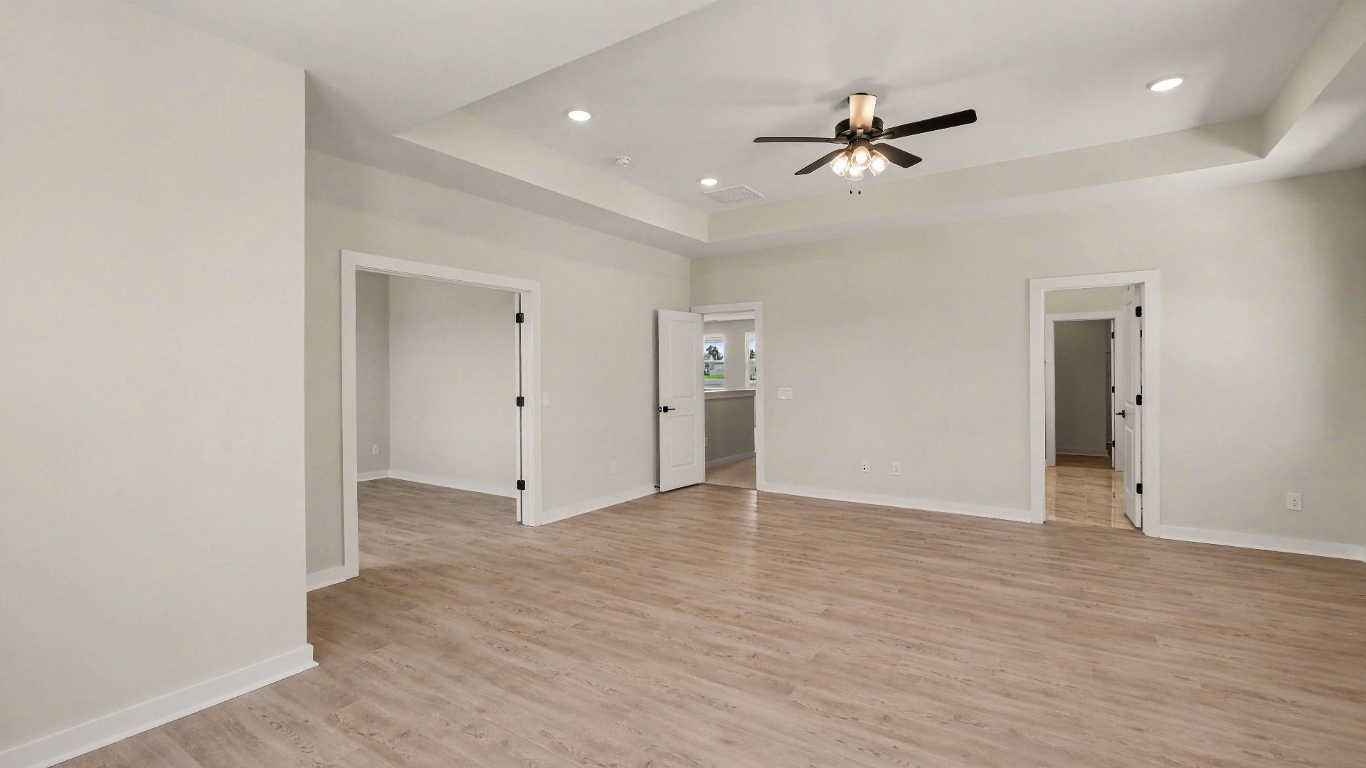 Primary bedroom with hardwood flooring and view of connected private study and en-suite bathroom