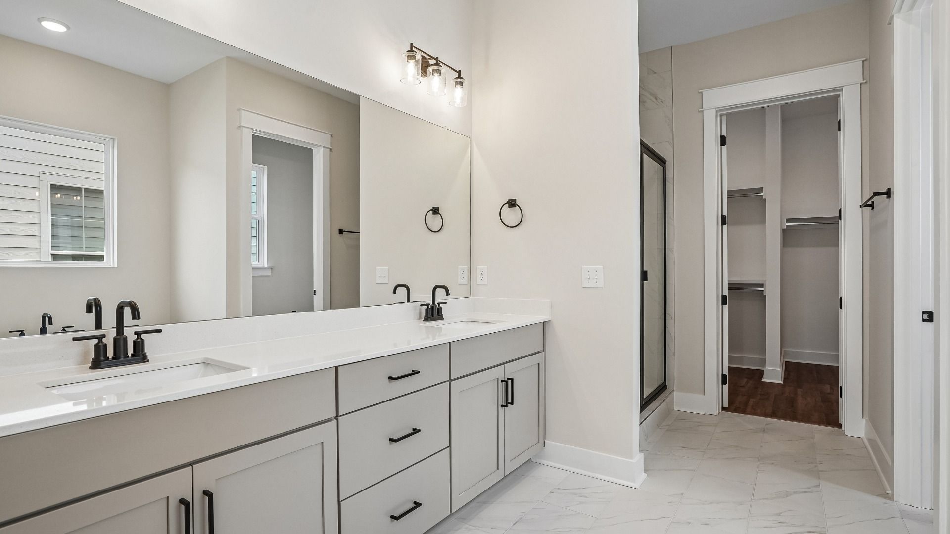 Primary bathroom with dual vanity, tile flooring, quartz countertops, shower, and walk-in closet