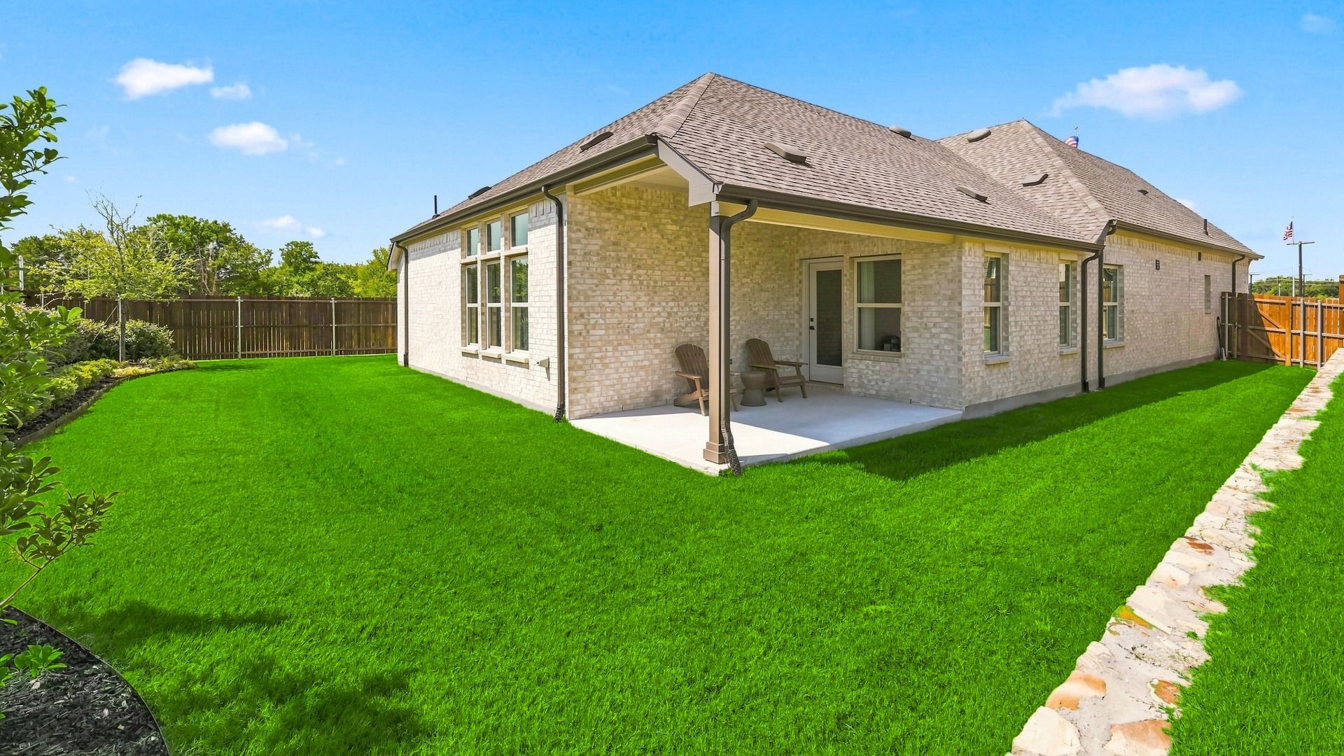 Elegant patio with brick facade and expansive lawn in Churchill. Modern fencing enhances privacy.
