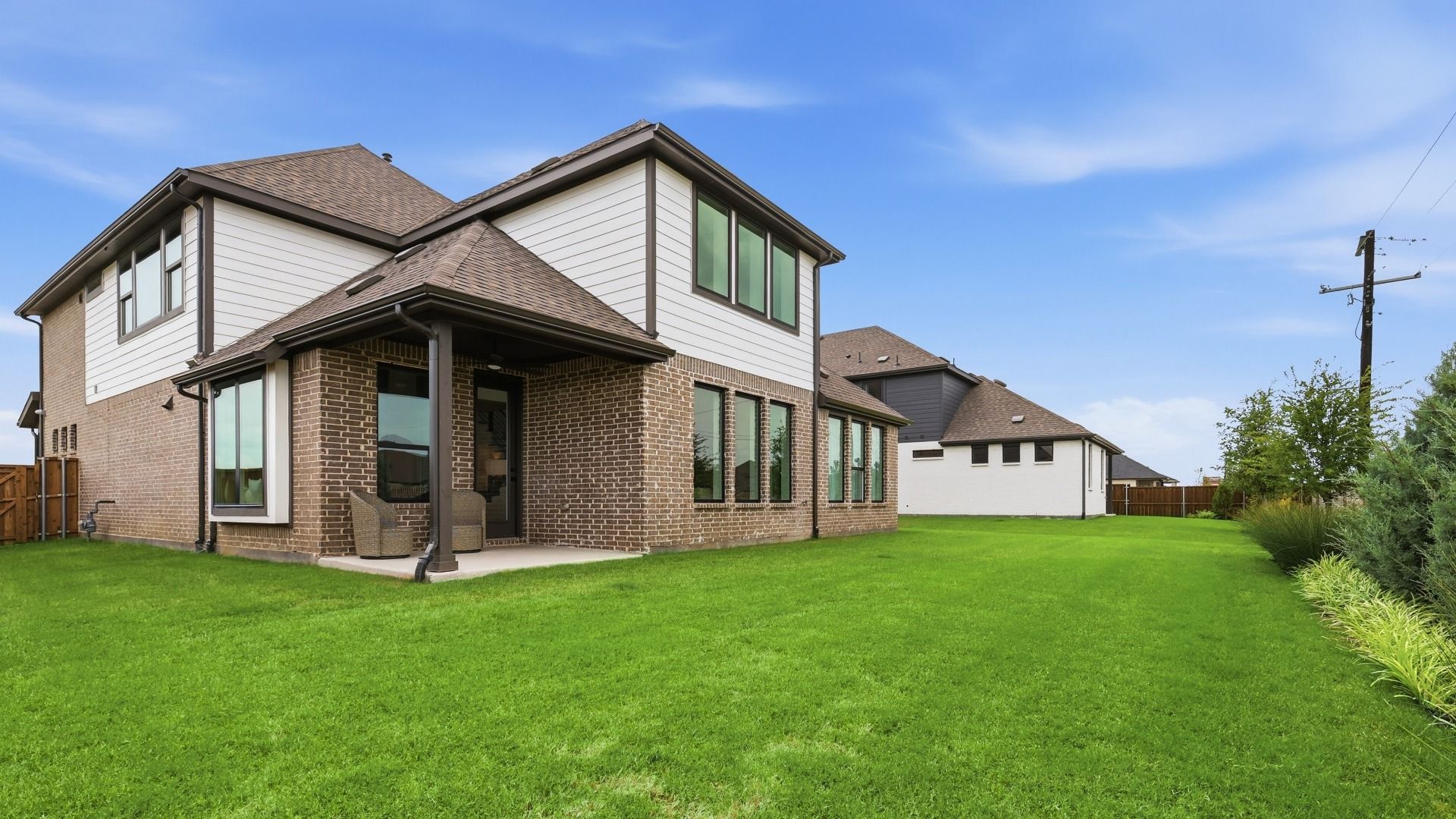 Elegant brick facade with expansive windows in Westridge showcases luxury living with a spacious backyard.