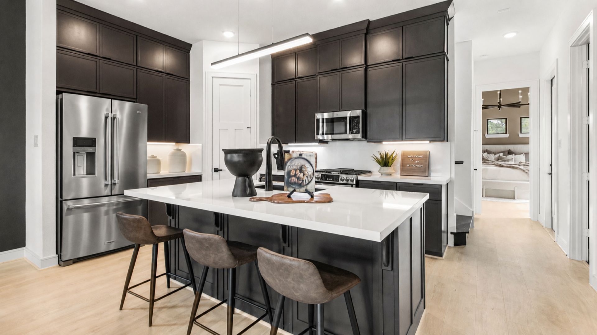 This modern kitchen in Bridgeland Central showcases sleek dark cabinets and white surfaces.