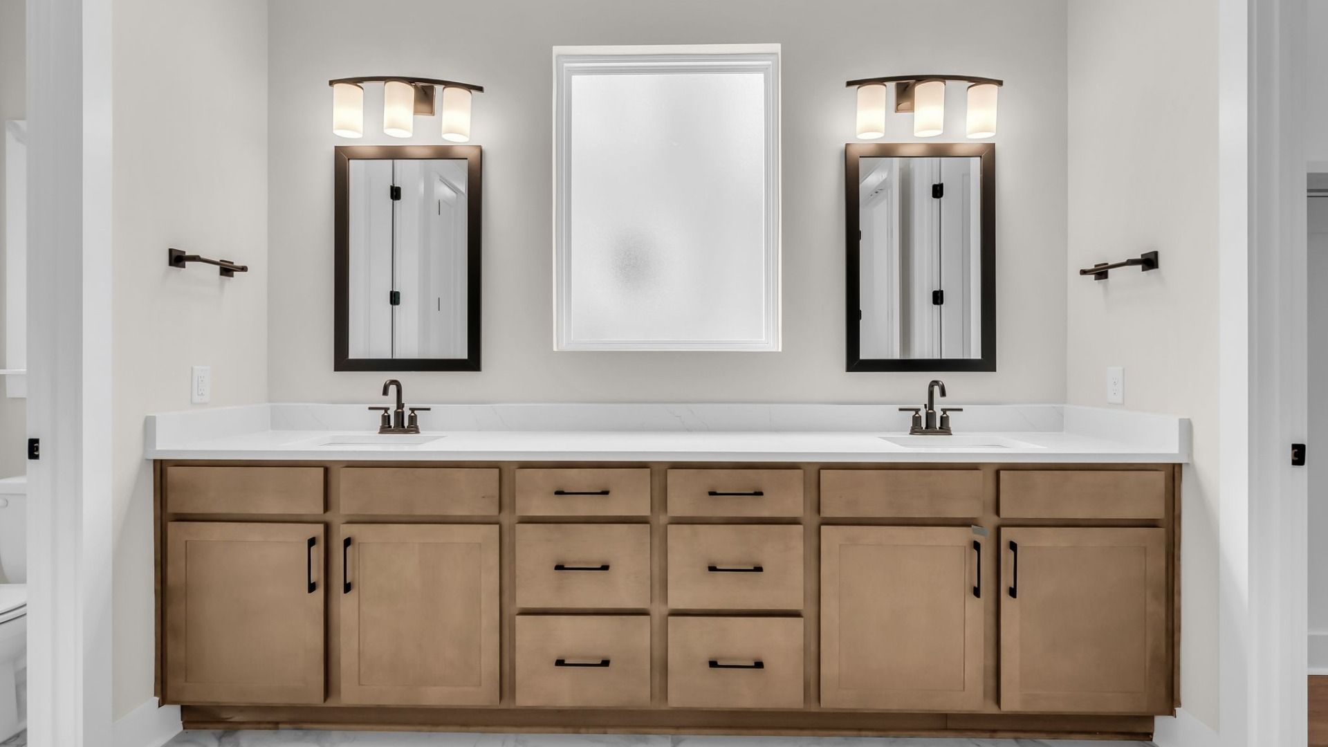 Primary suite bathroom with dual-vanity and natural light