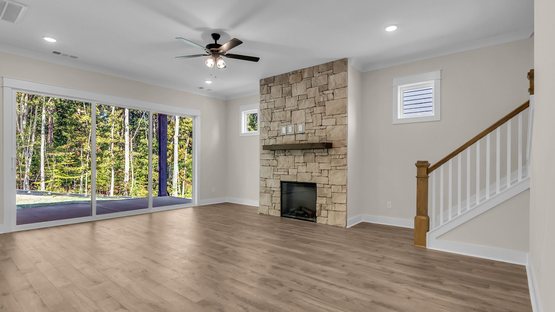 Living room with central fireplace and large rear windows (Representative of completed home)