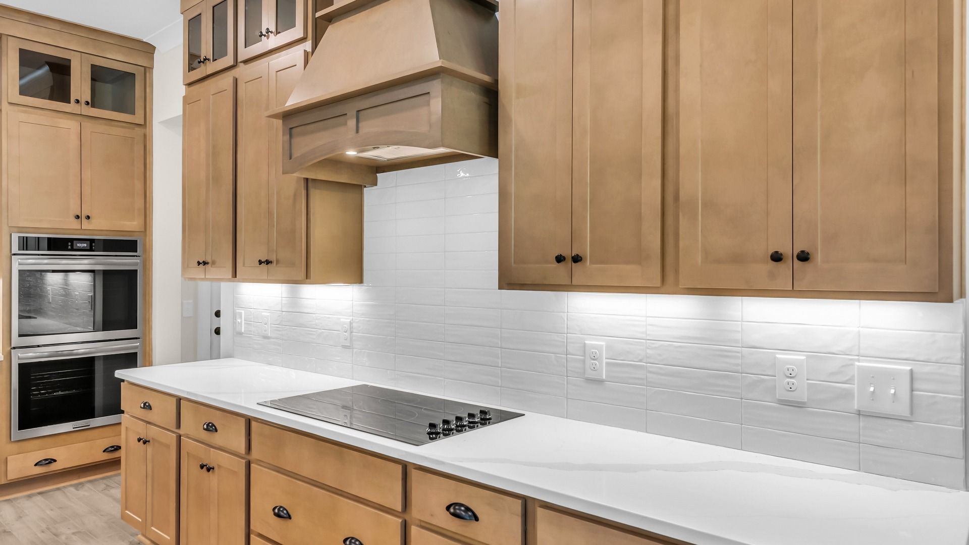 Kitchen with wood colored cabinetry and nearby gathering room (Representative of completed home)