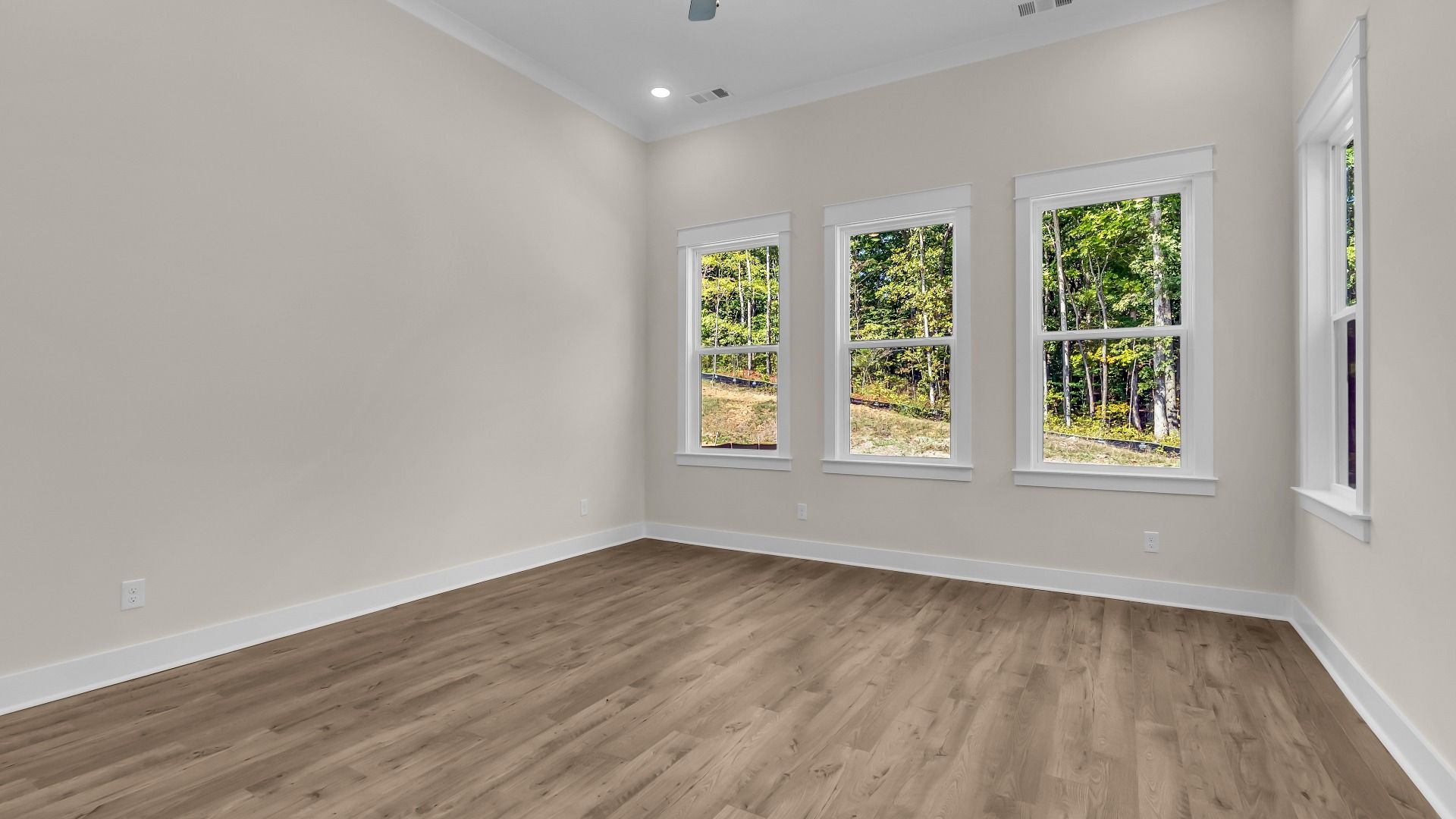 First floor bedroom with windows on multiple sides and hard surface flooring (Representative of completed home)