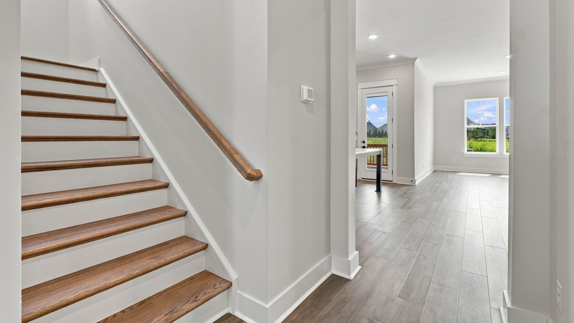 Stairway featuring elevated features such as accented wood and railing before you enter the kitchen area.