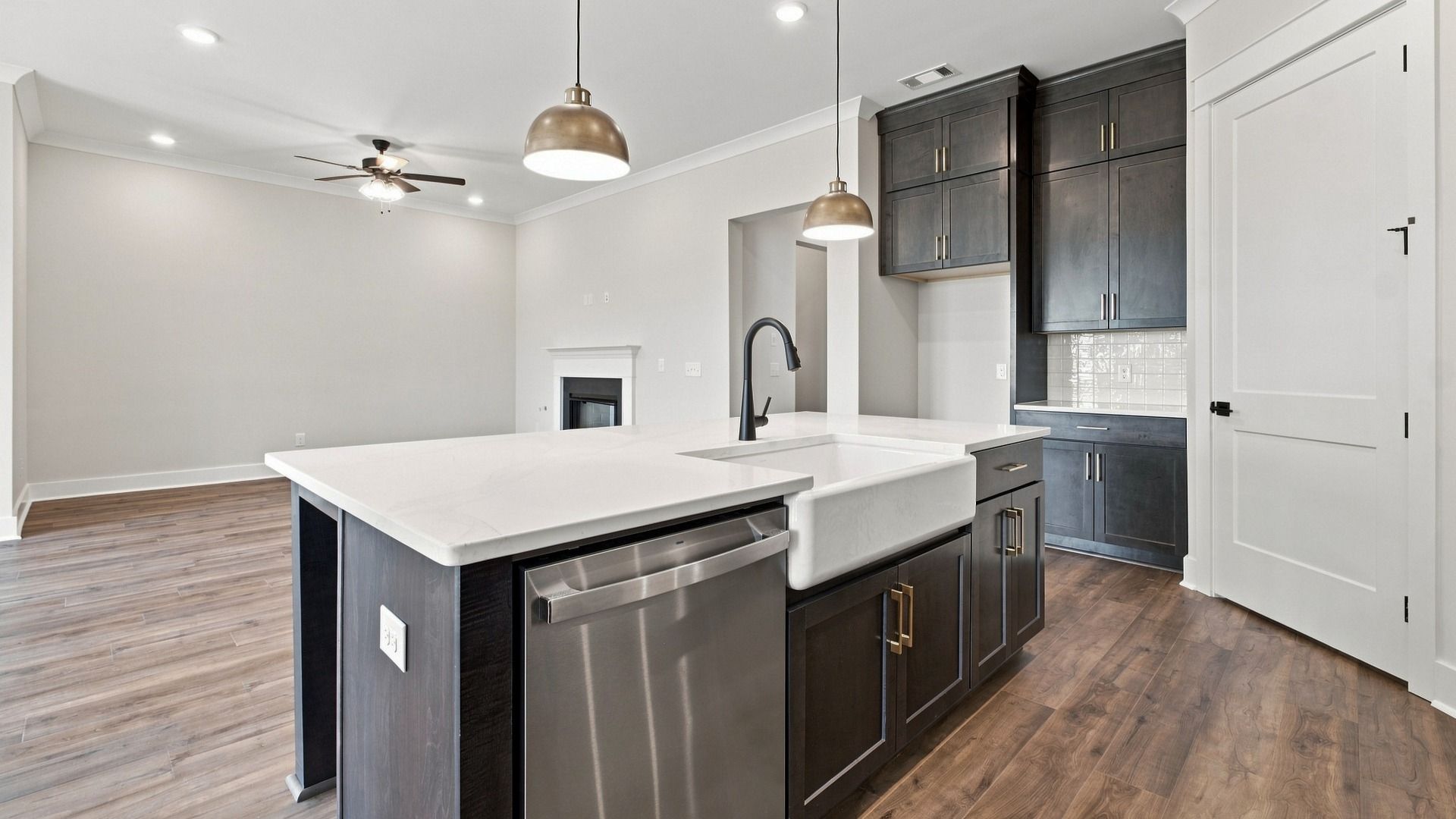 Kitchen island featuring quartz countertops with dishwasher and sink in the middle of spacious dining space.