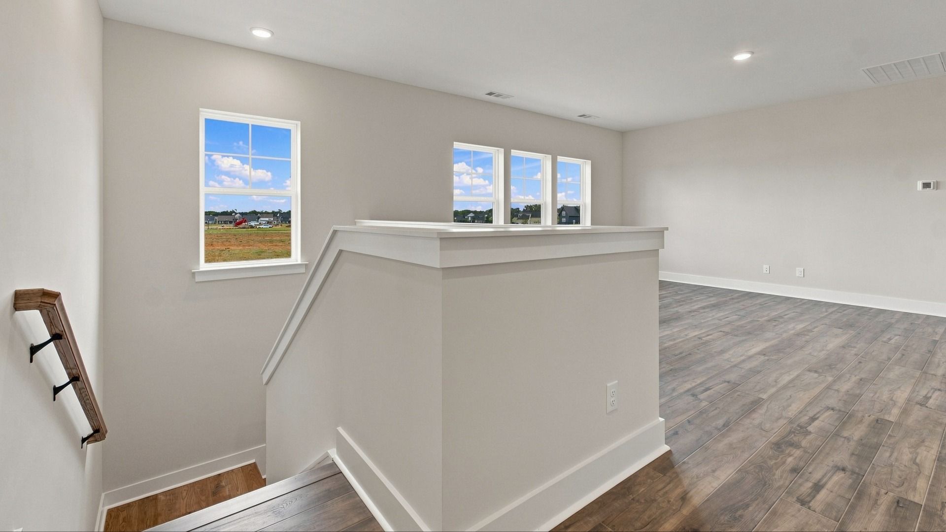 Versatile living area right off the stairway featuring four windows for natural light.