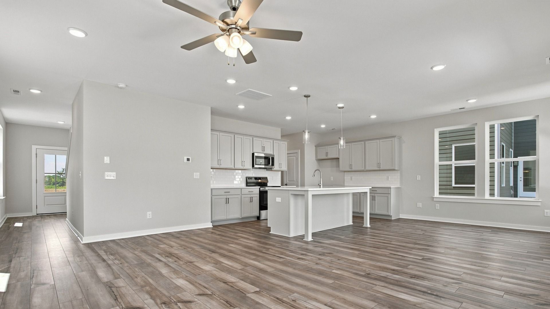 View of spacious kitchen from back windows with natural light highlighting elevated flooring