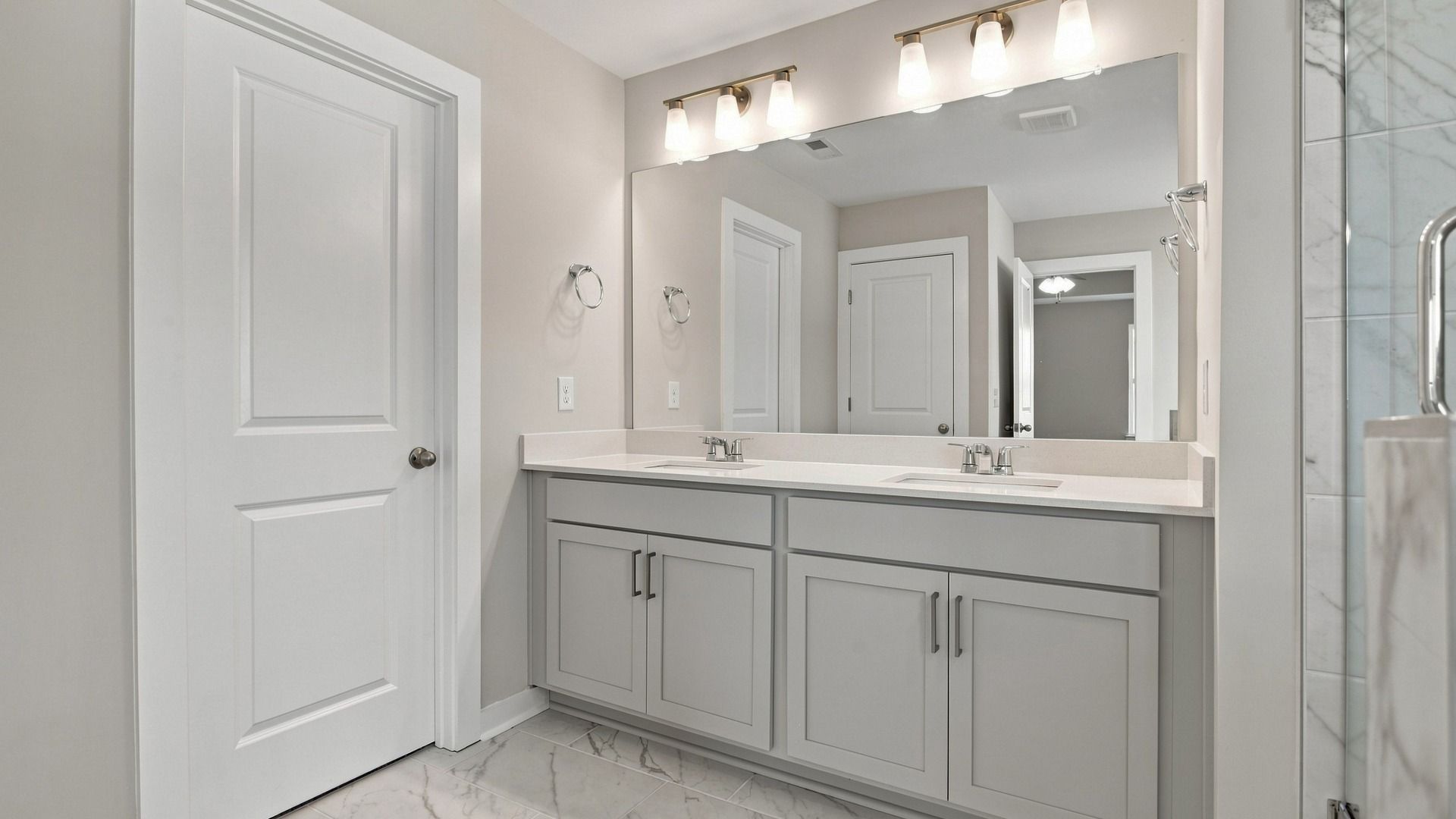 Dual vanities with sizeable mirror next to walk-in closet and shower