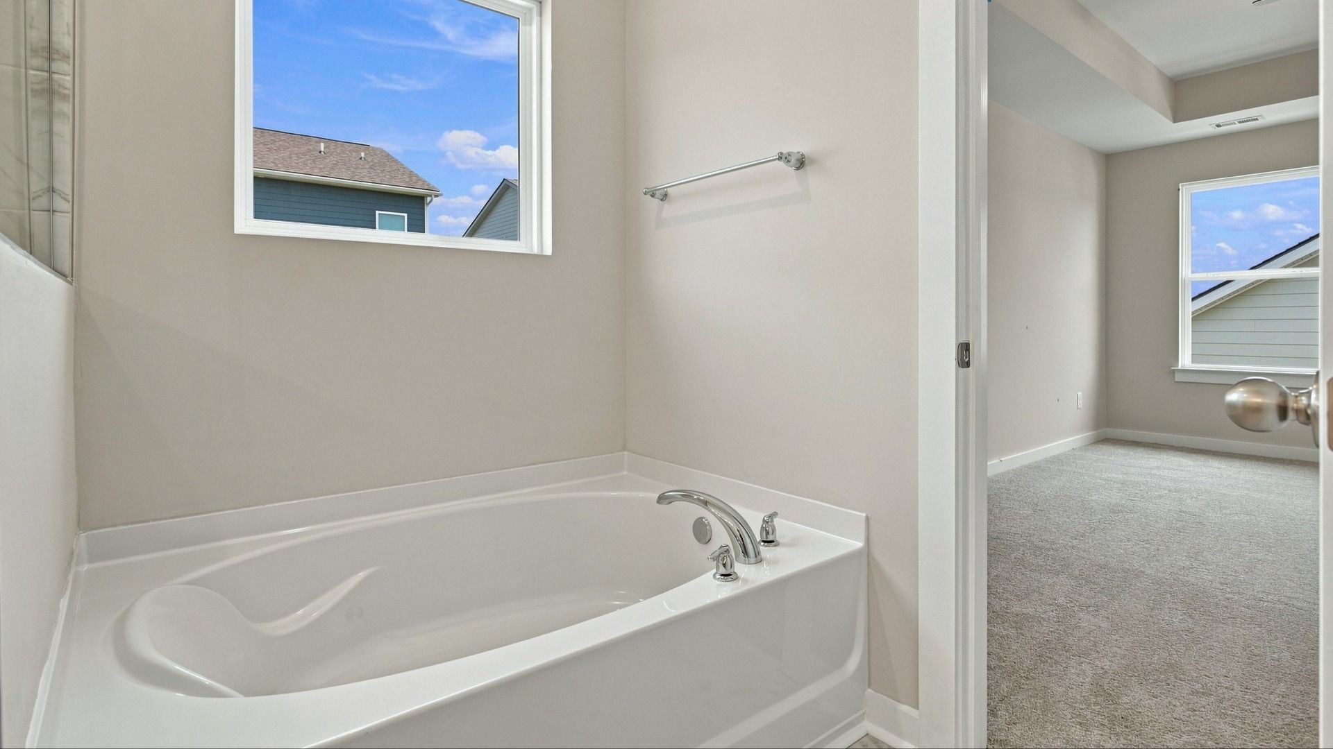 Bathtub with window above next to bathroom entryway