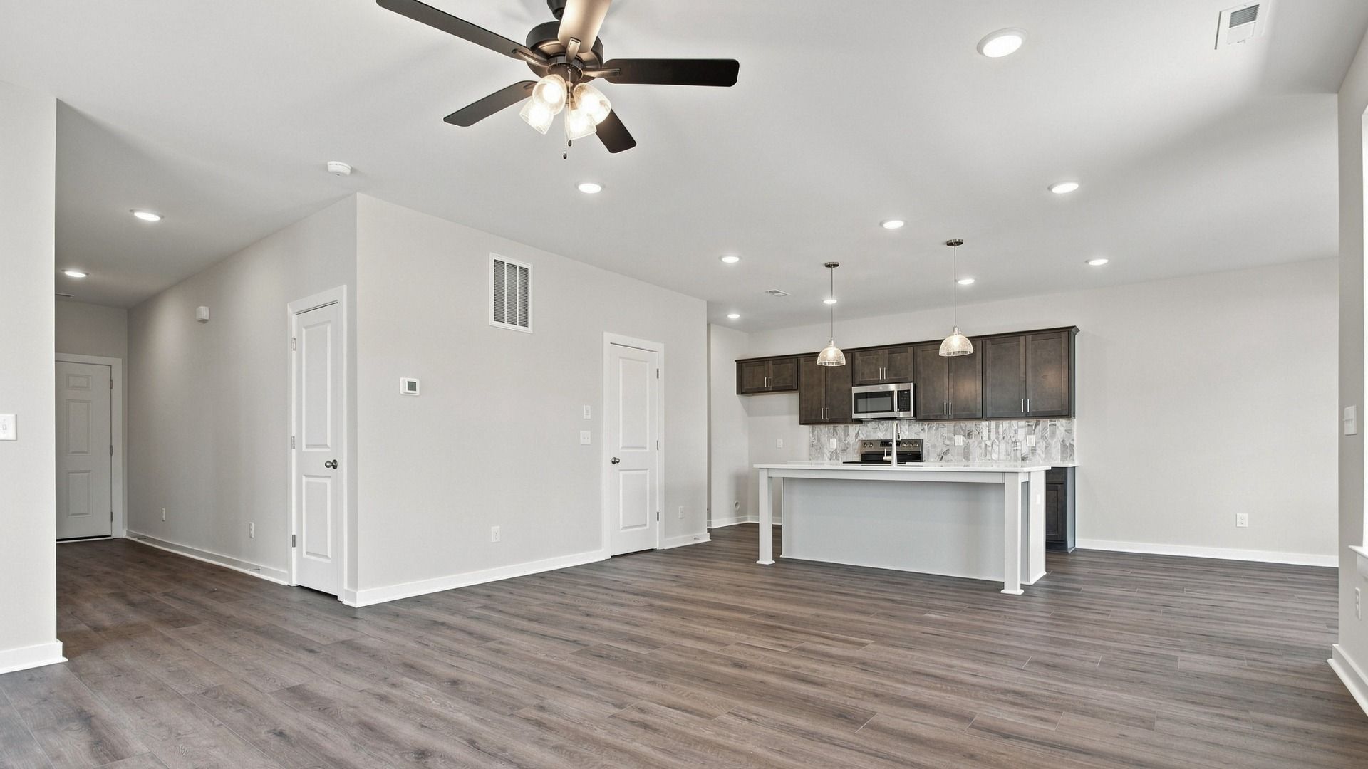 Versatile living/dining area with ceiling fan and modern light fixtures