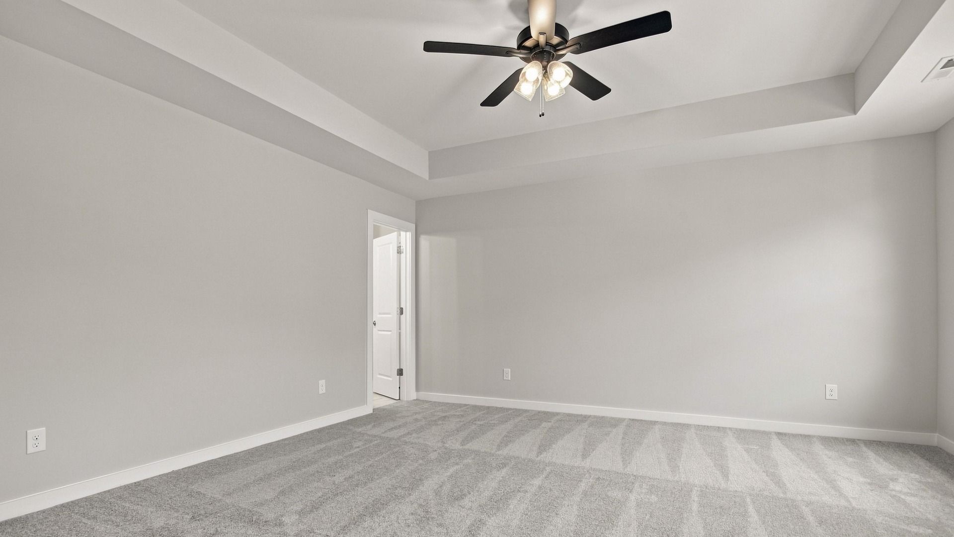 Spacious primary bedroom with elevated tray ceiling feature