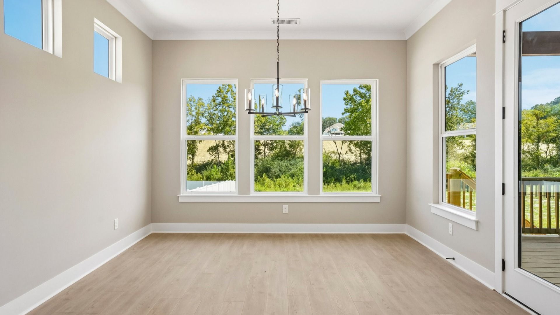 Dining area with various windows and hanging light next to backyard door