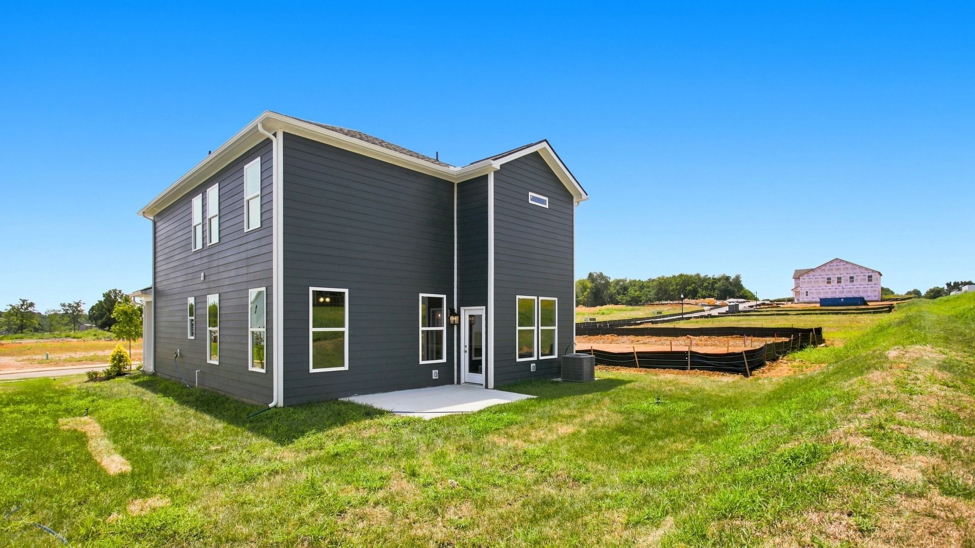 Backyard and Exterior of two story home with blue siding and concrete patio