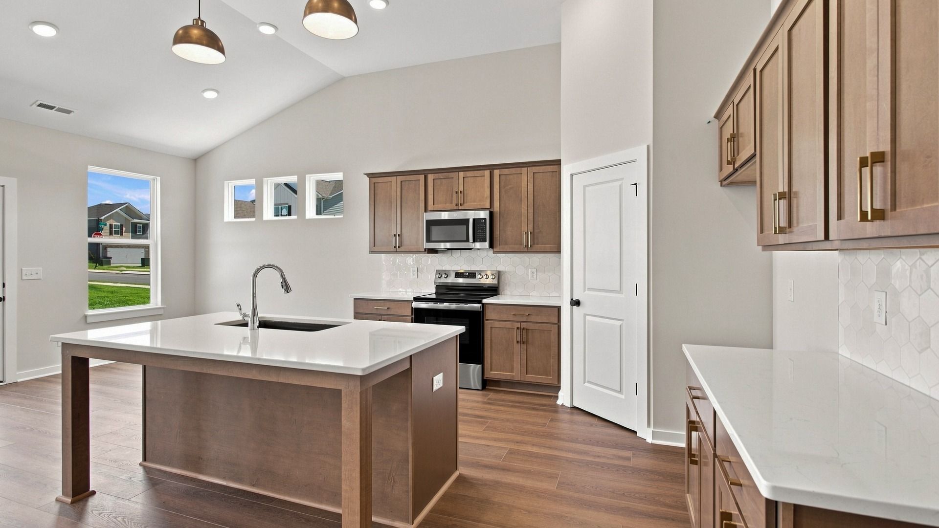 Kitchen Layout with ceramic tile backsplash, quartz countertops, and kitchen island
