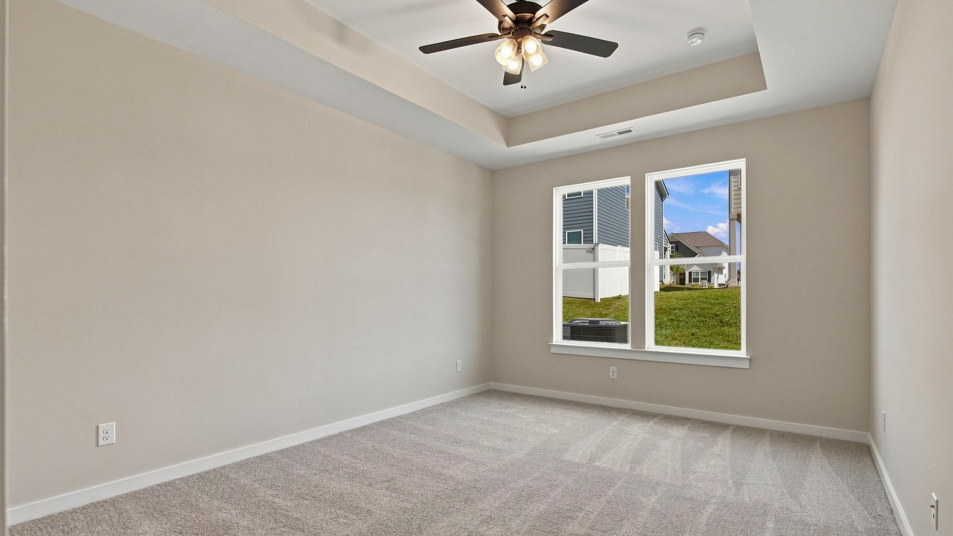 Primary bedroom with large windows, tray ceiling, and ceiling fan