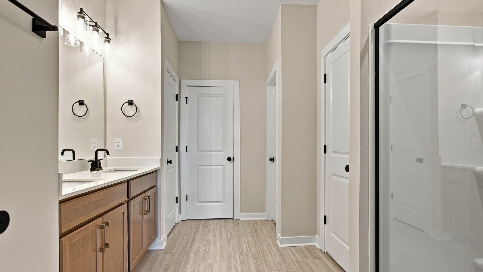 Primary bathroom with dual vanity, shower, storage, and walk-in closet