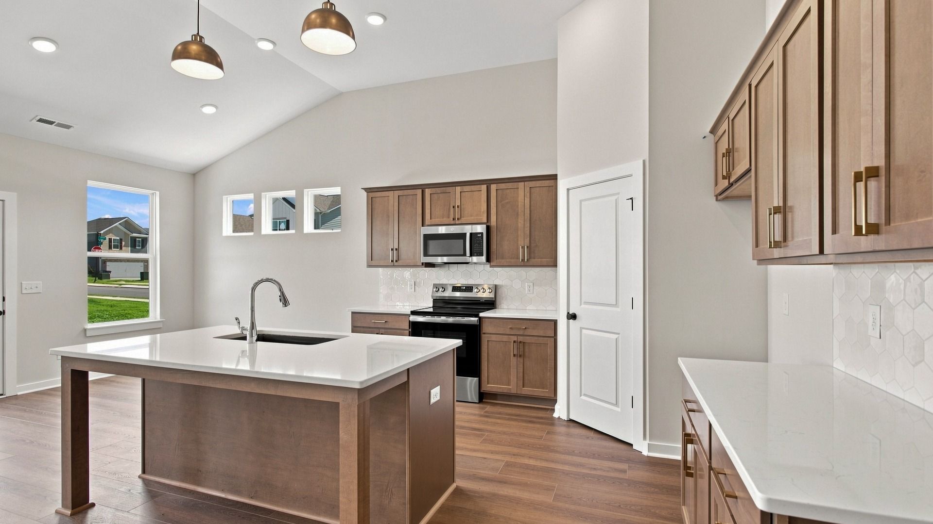 Kitchen with ceramic tile backsplash, quartz countertops, and stainless steel appliances