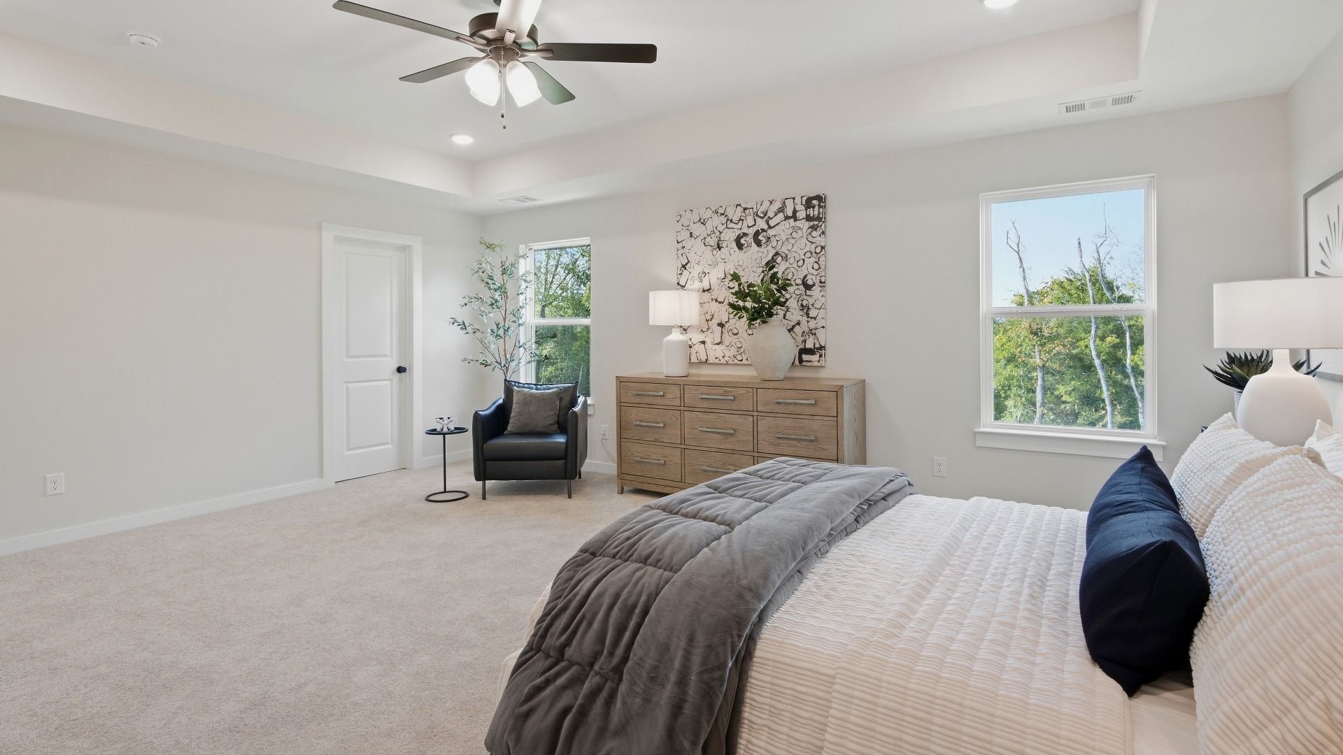 Elevated primary bedroom with windows and ceiling fan
