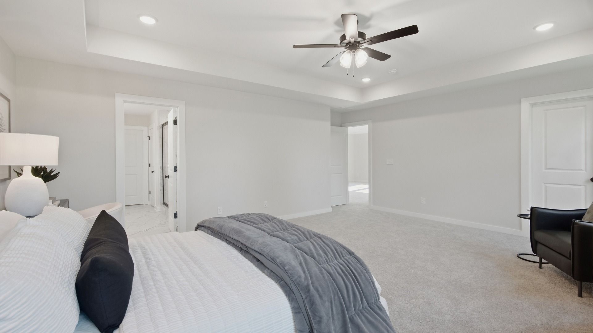 Spacious primary bedroom with tray ceilings and connected bathroom and walk-in closet