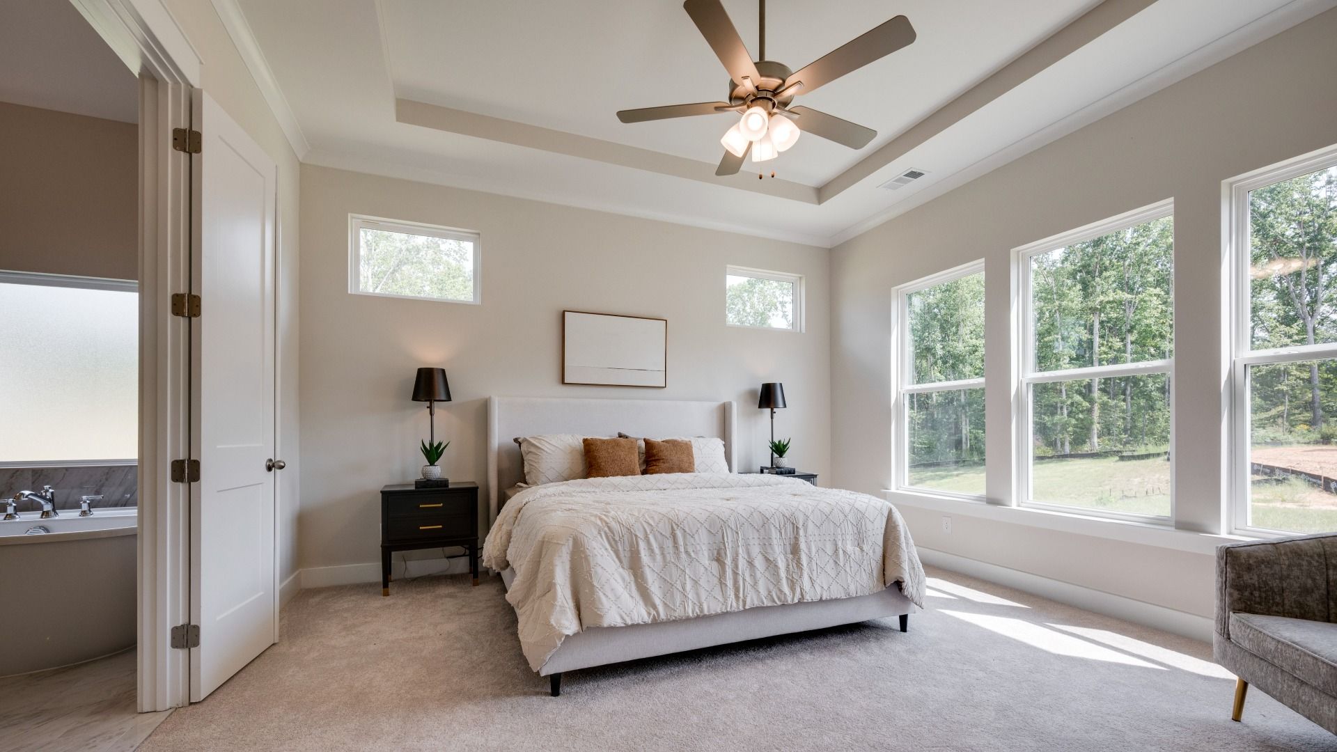 Primary bedroom with trey ceilings and sizeable windows connected to bathroom and walk-in closet