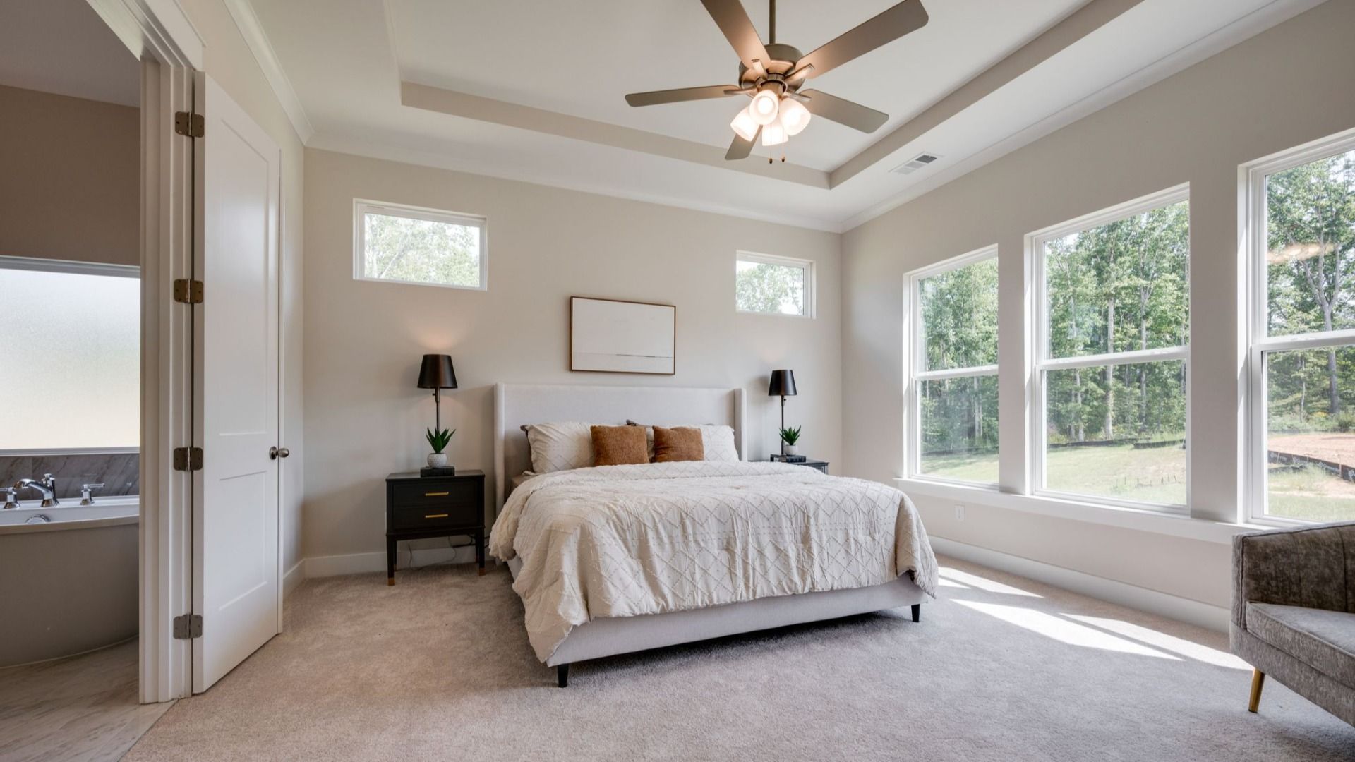 Primary bedroom with trey ceilings and sizeable windows connected to bathroom and walk-in closet