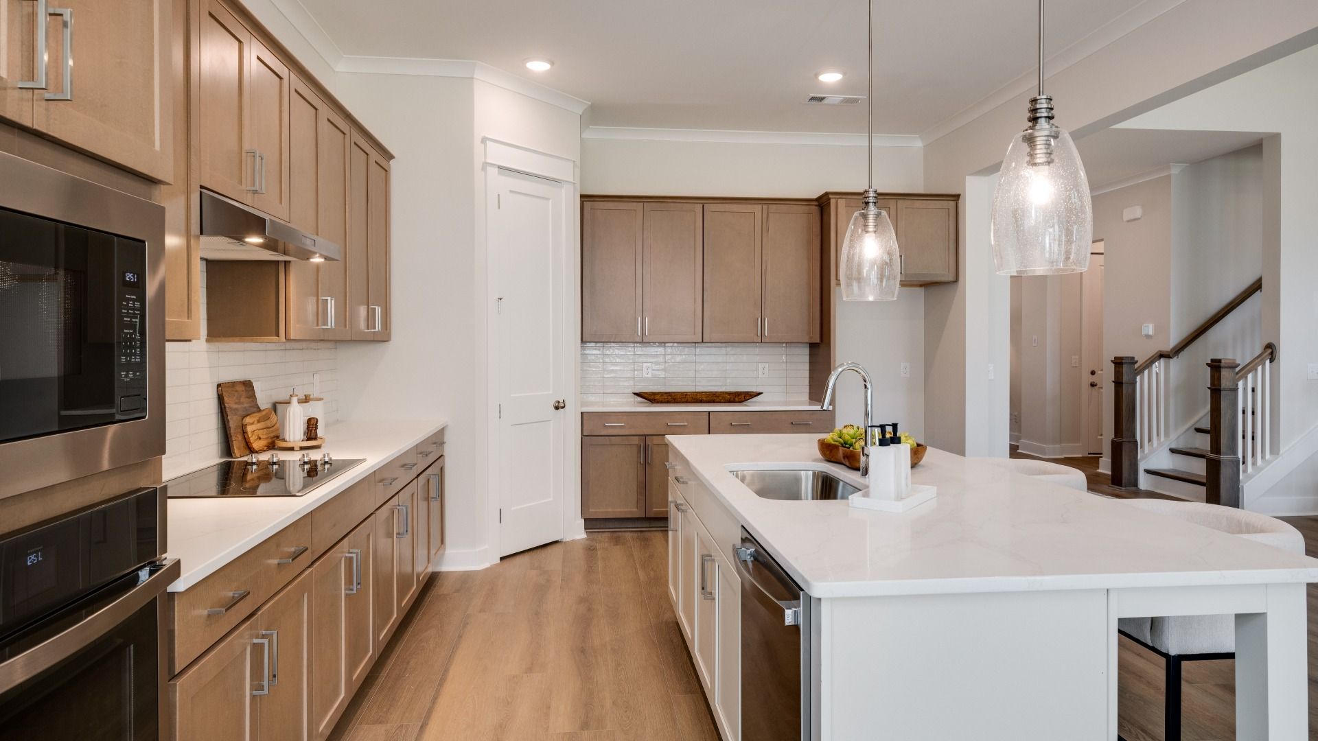Sink and dishwasher paired with kitchen island next to staircase