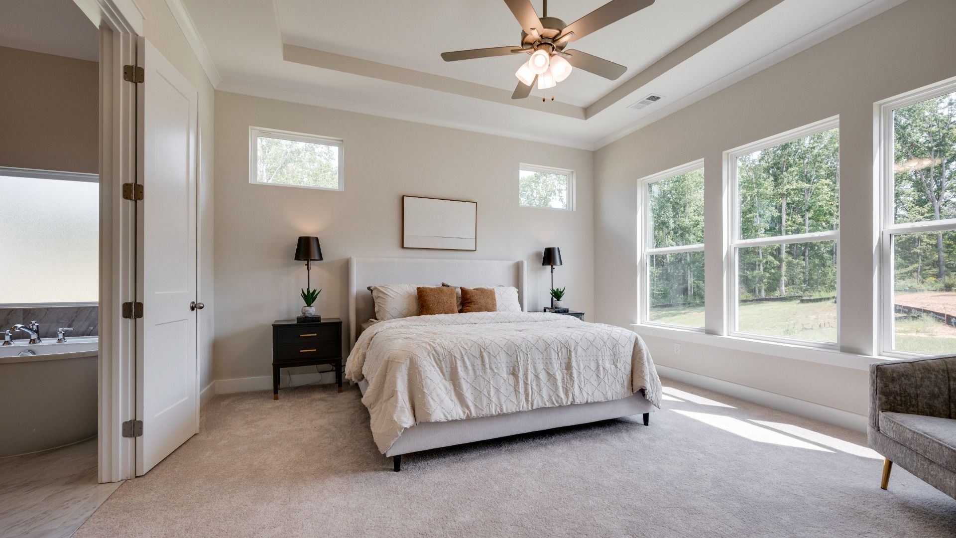 Primary bedroom with trey ceilings and sizeable windows connected to bathroom and walk-in closet