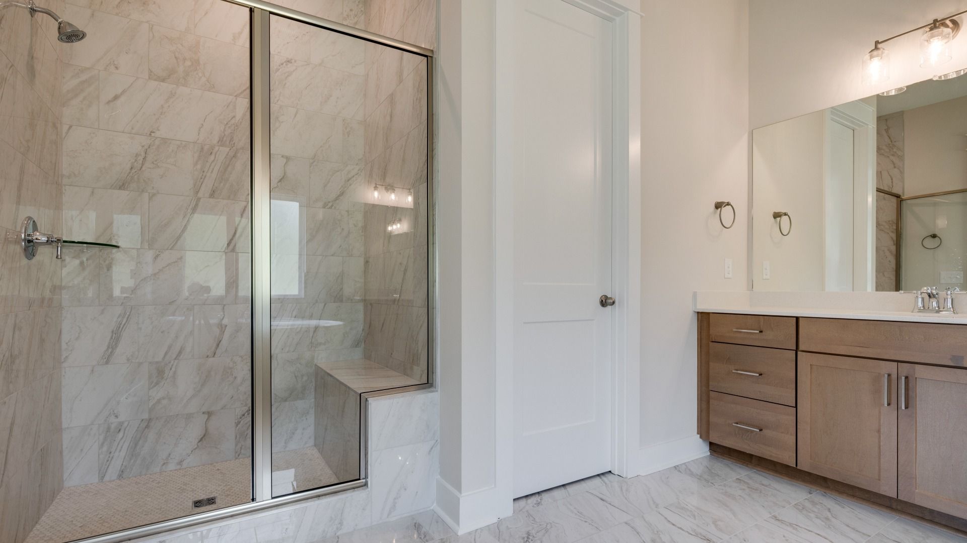 Large tiled primary bathroom with multiple vanities, glass shower enclosure, and freestanding tub