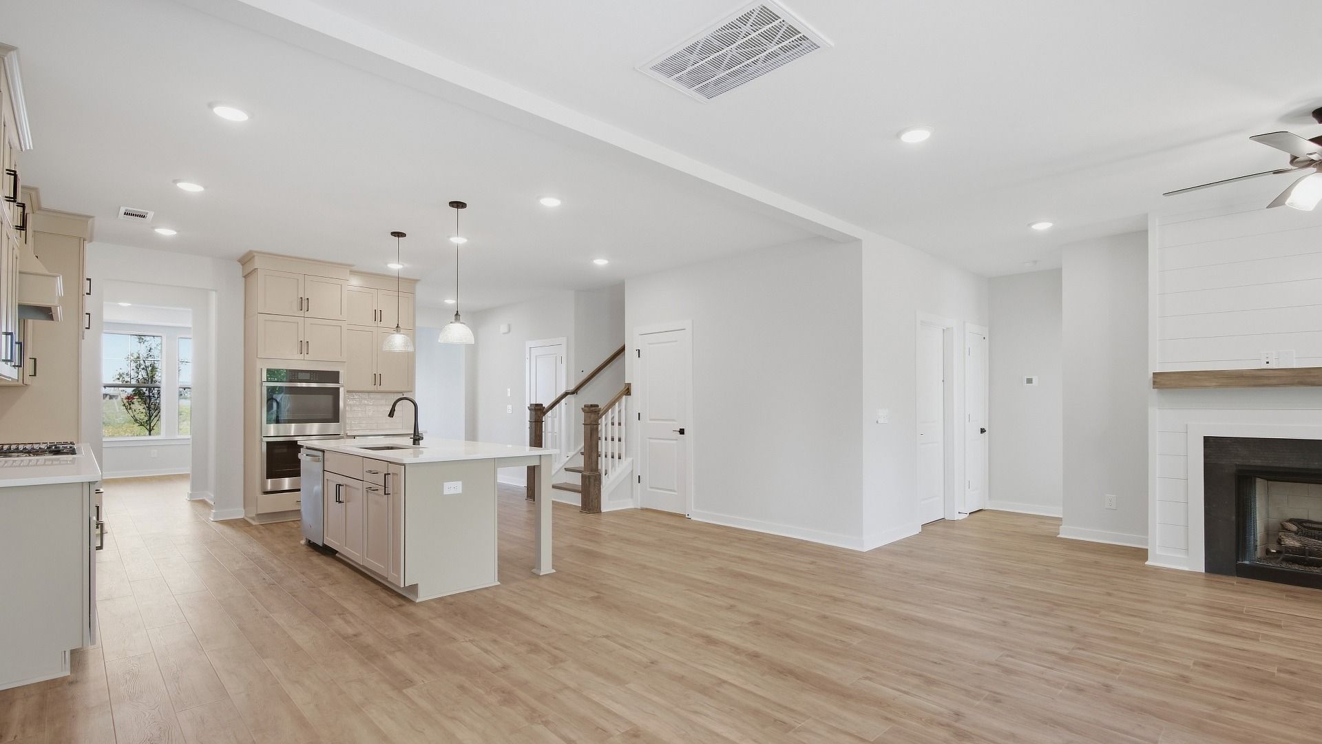 Living area next to kitchen and dining areas with hard wood flooring