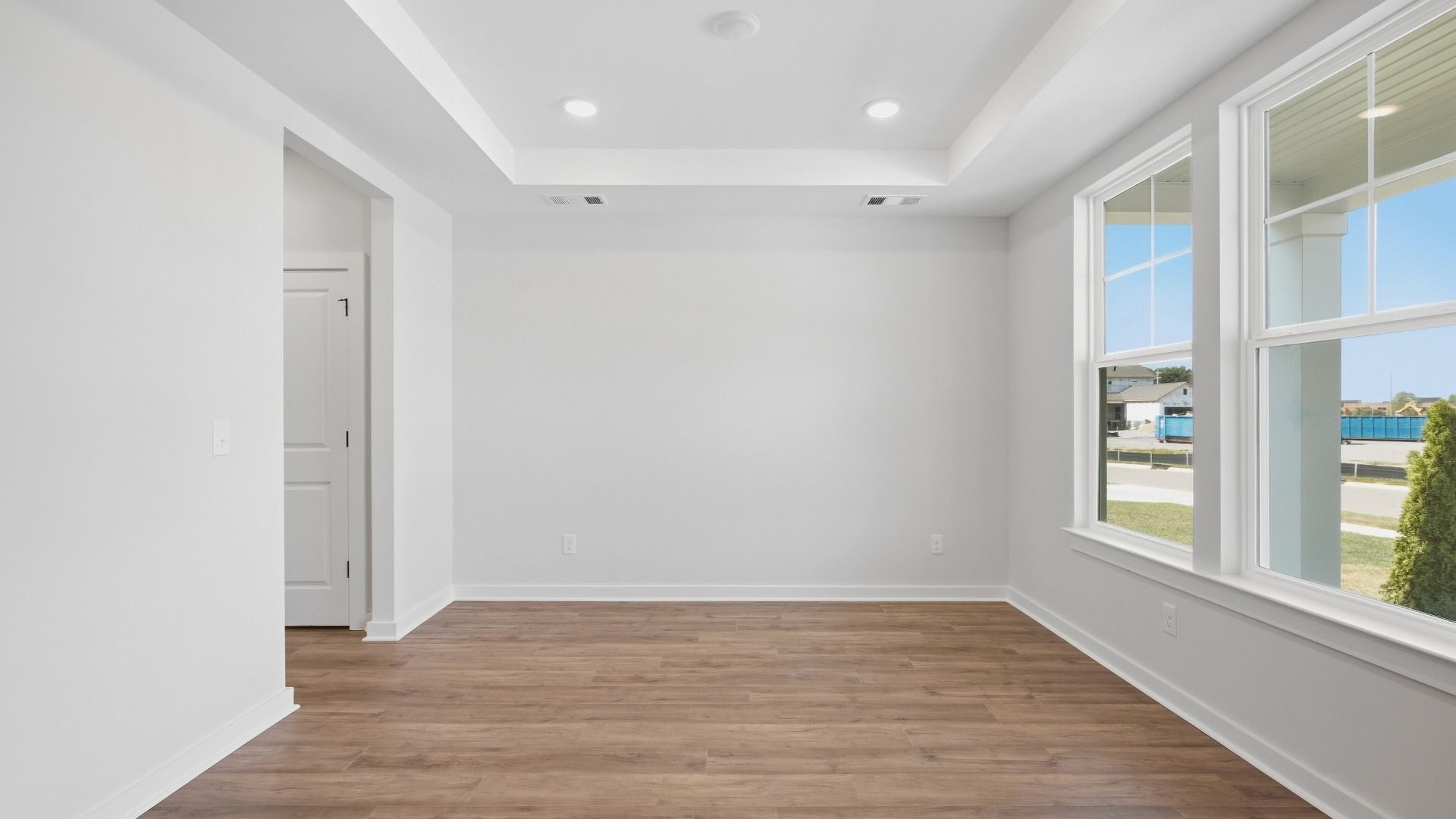 Versatile living space right next to front door entrance with elevated trey ceilings