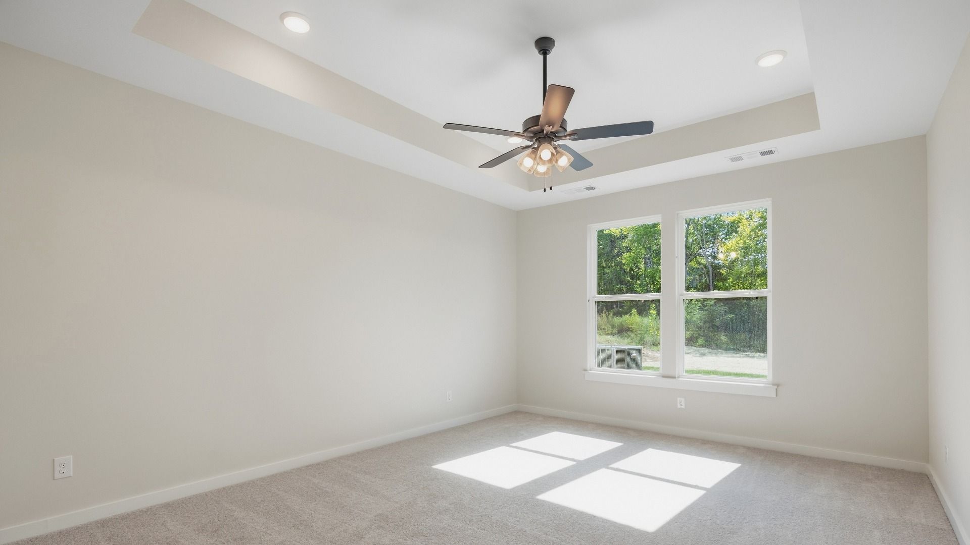 Primary bedroom with window with trey ceiling and fan