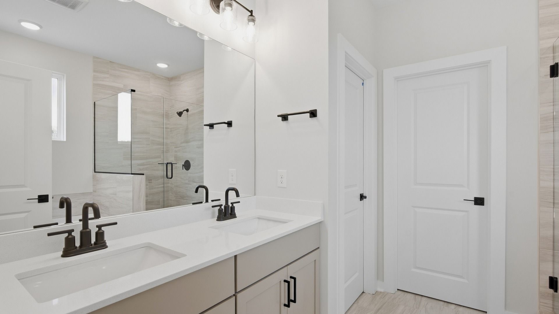 Primary bathroom with dual vanities and sizeable mirror