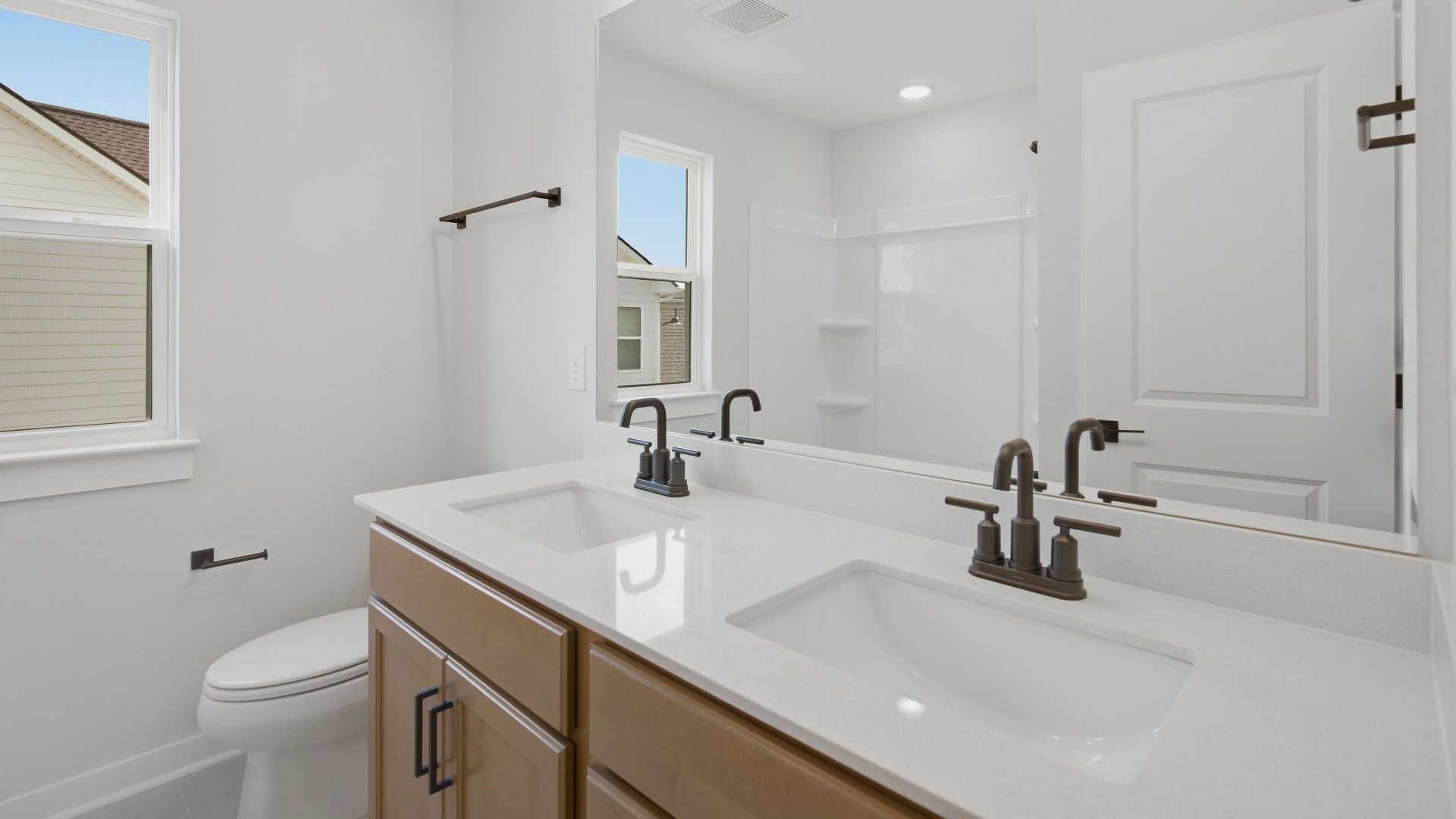 Secondary bathroom with dual vanities and bathtub with window