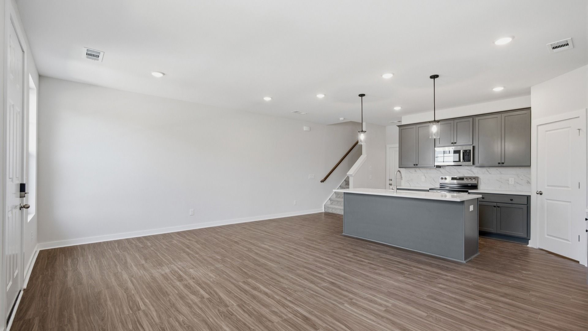 Kitchen with island and pantry door next to entryway and stairs