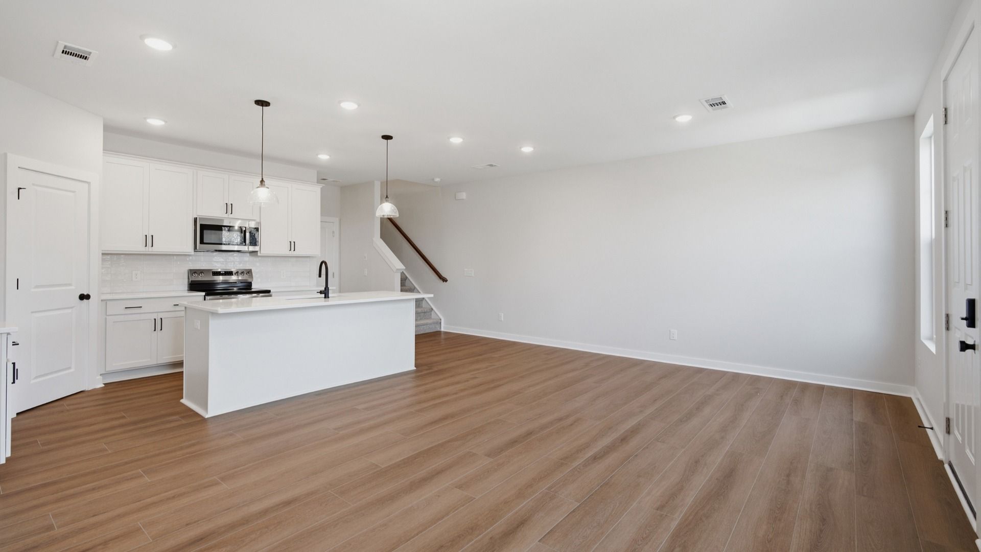Kitchen with island and pantry door next to entryway and stairs