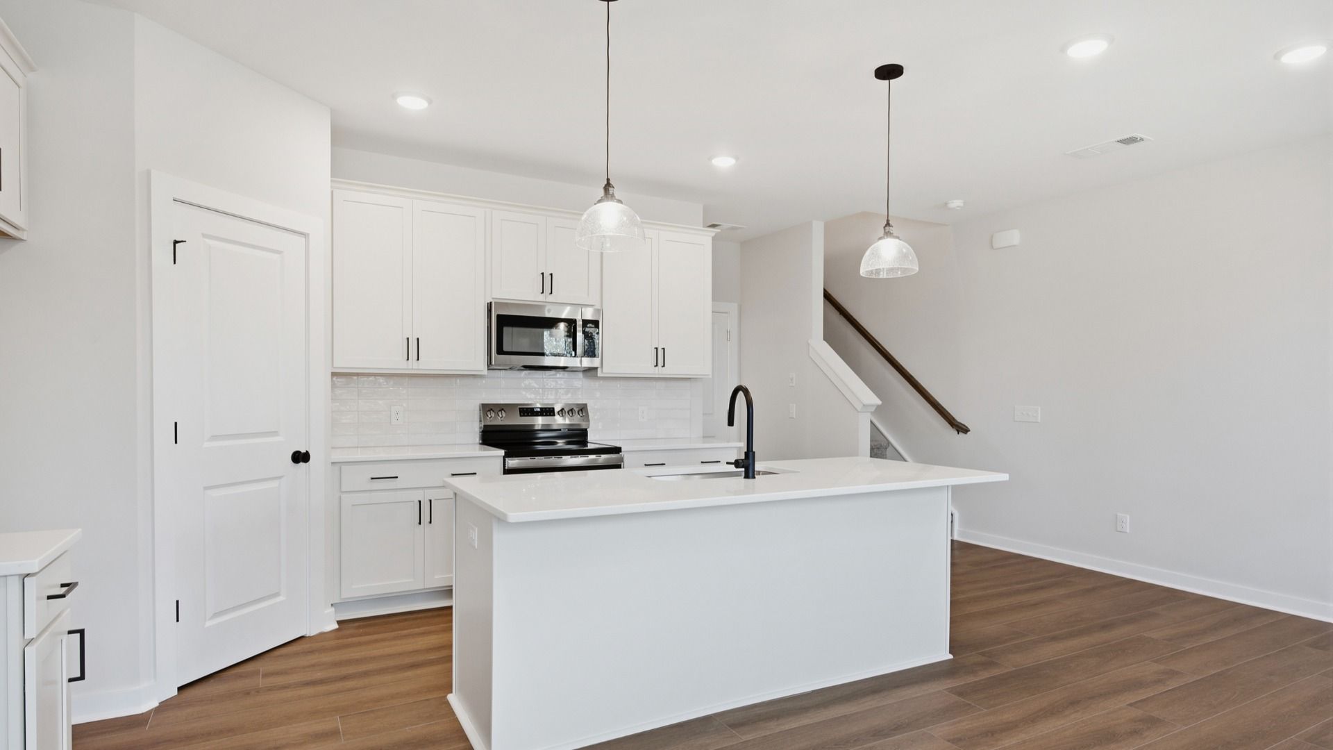 Kitchen with tile backsplash, quartz countertops, and pendant lighting