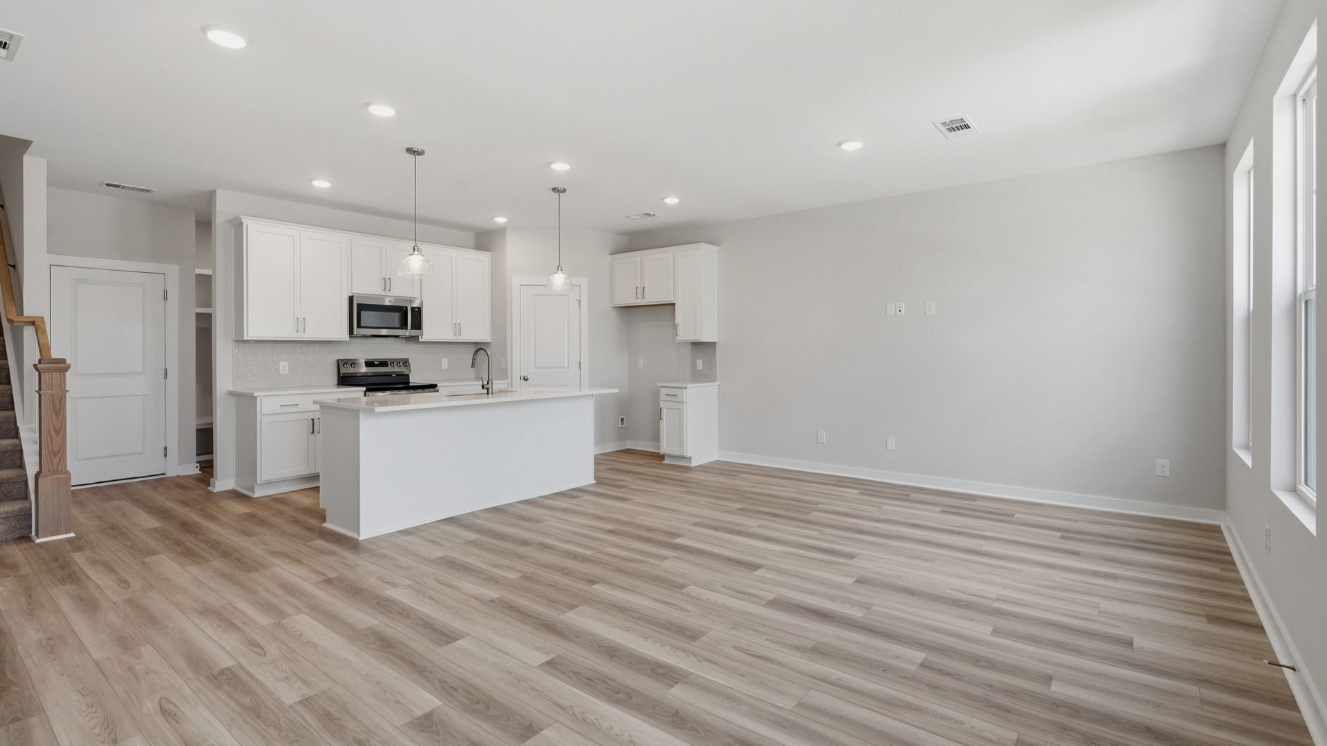 Kitchen with island and pantry door next to entryway and stairs