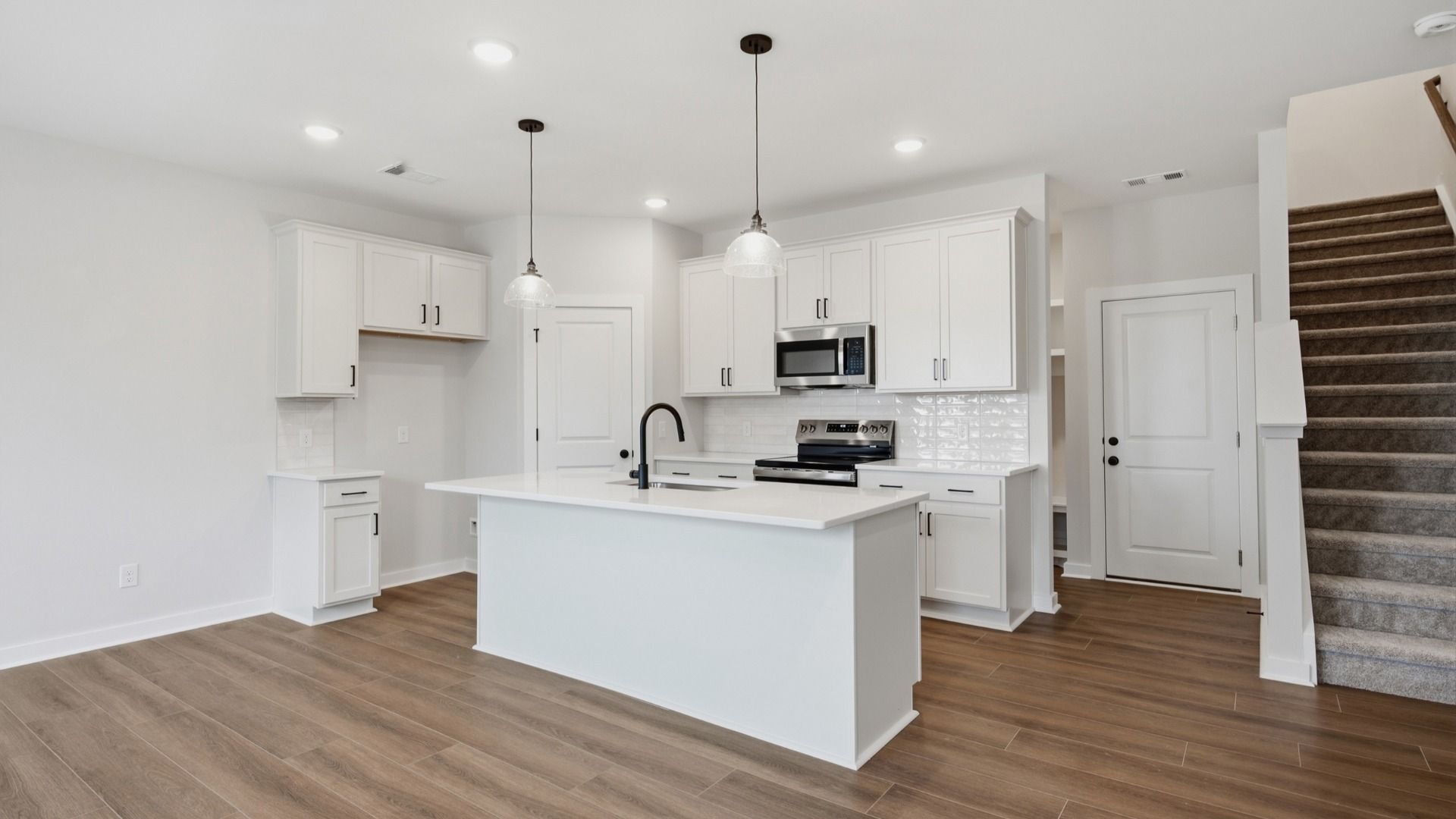 Kitchen with white cabinets and white island under hanging lights