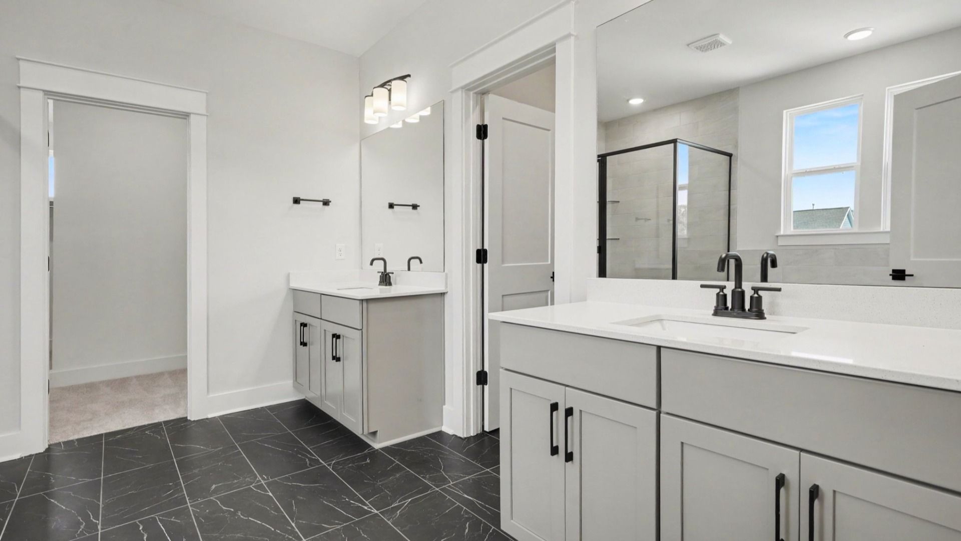 Elevated primary bathroom with dual vanities next to walk-in closet