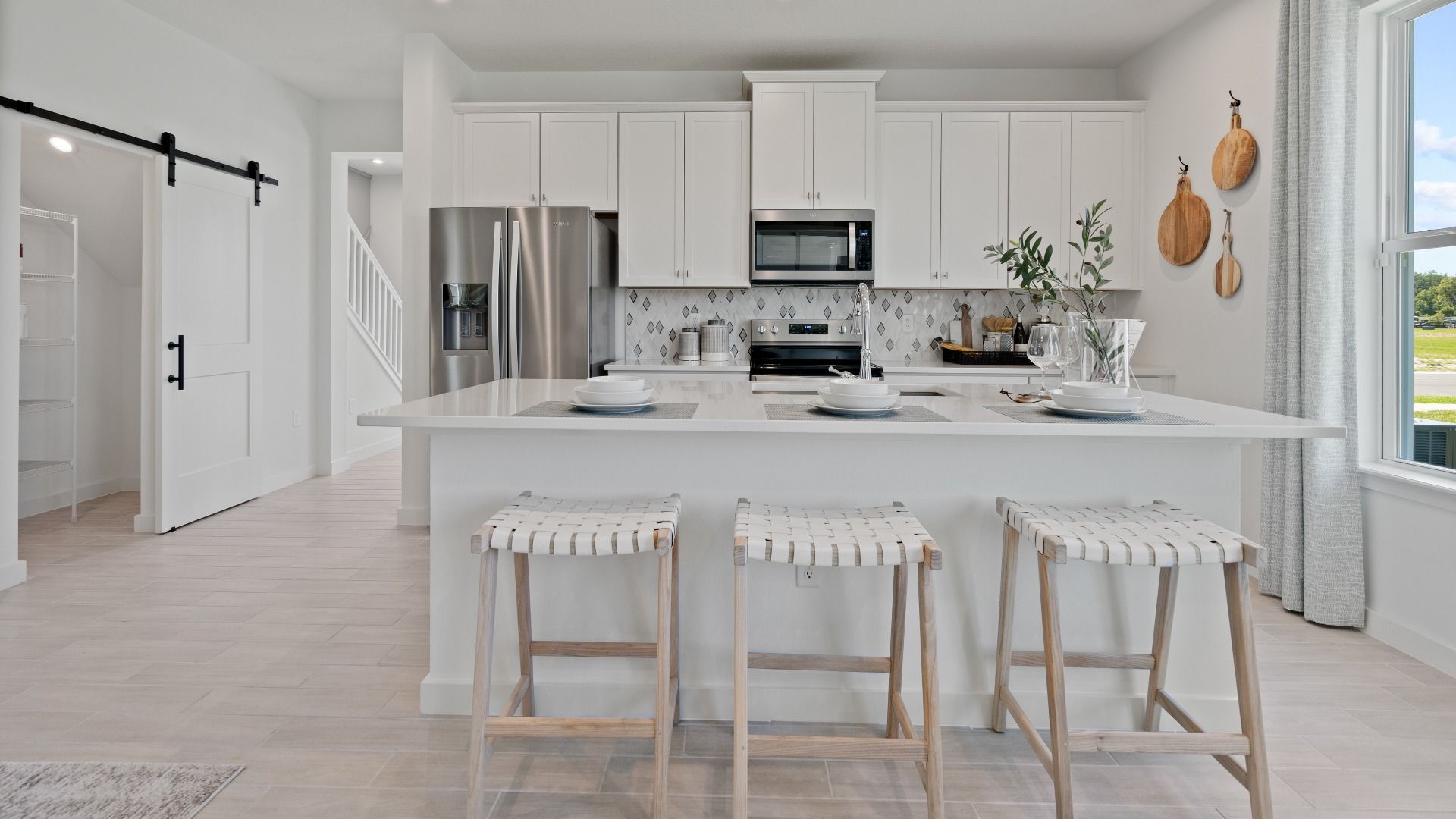 Open kitchen with white cabinets and large island at a DRB Homes Ambersweet model at the Trinity Place community.