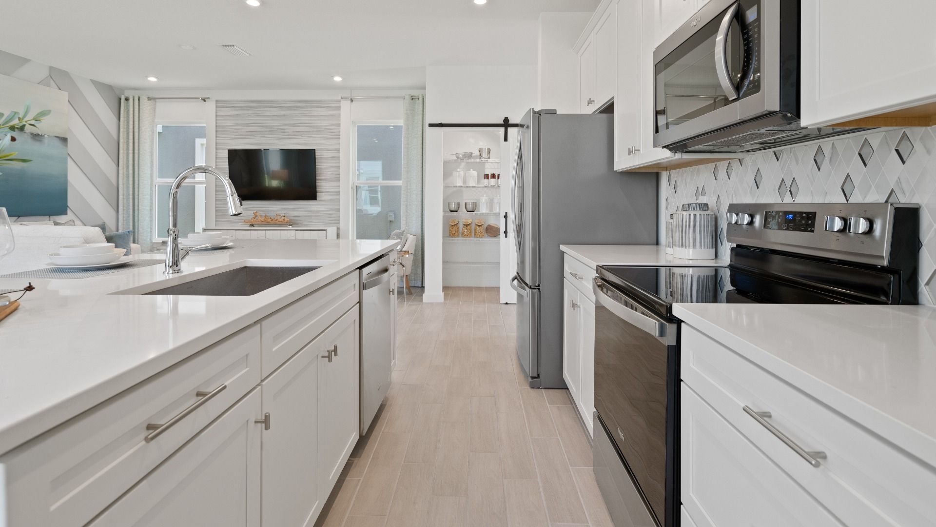 Open kitchen with white cabinets and large island at a DRB Homes Ambersweet model at the Trinity Place community.