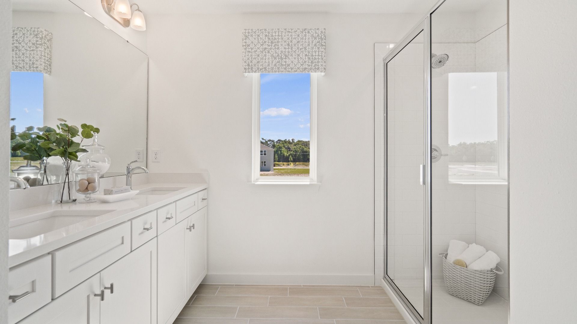Primary bath with dual sink vanity, step-i shower and window n a DRB Homes Ambersweet model at the Trinity Place community.