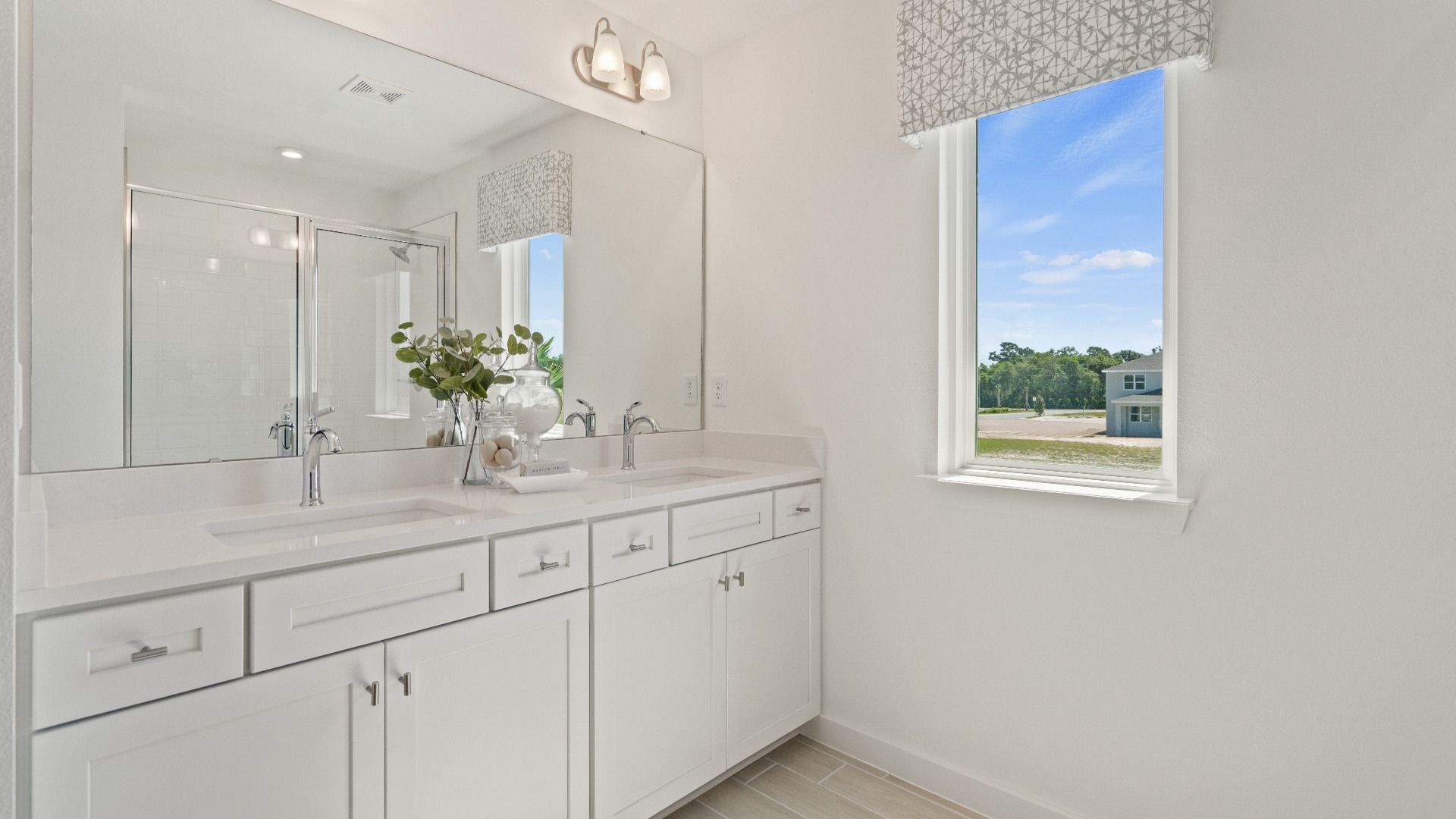 Primary bath with dual sink vanity, step-i shower and window n a DRB Homes Ambersweet model at the Trinity Place community.