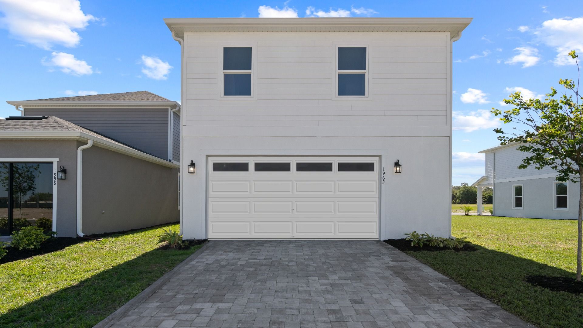 Exterior rear 2 car garage, above retreat with 2 large windows in a DRB Homes Ambersweet model at Trinity Place community.