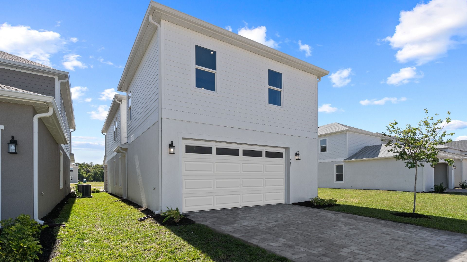 Exterior rear 2 car garage, above retreat with 2 large windows in a DRB Homes Ambersweet model at Trinity Place community.