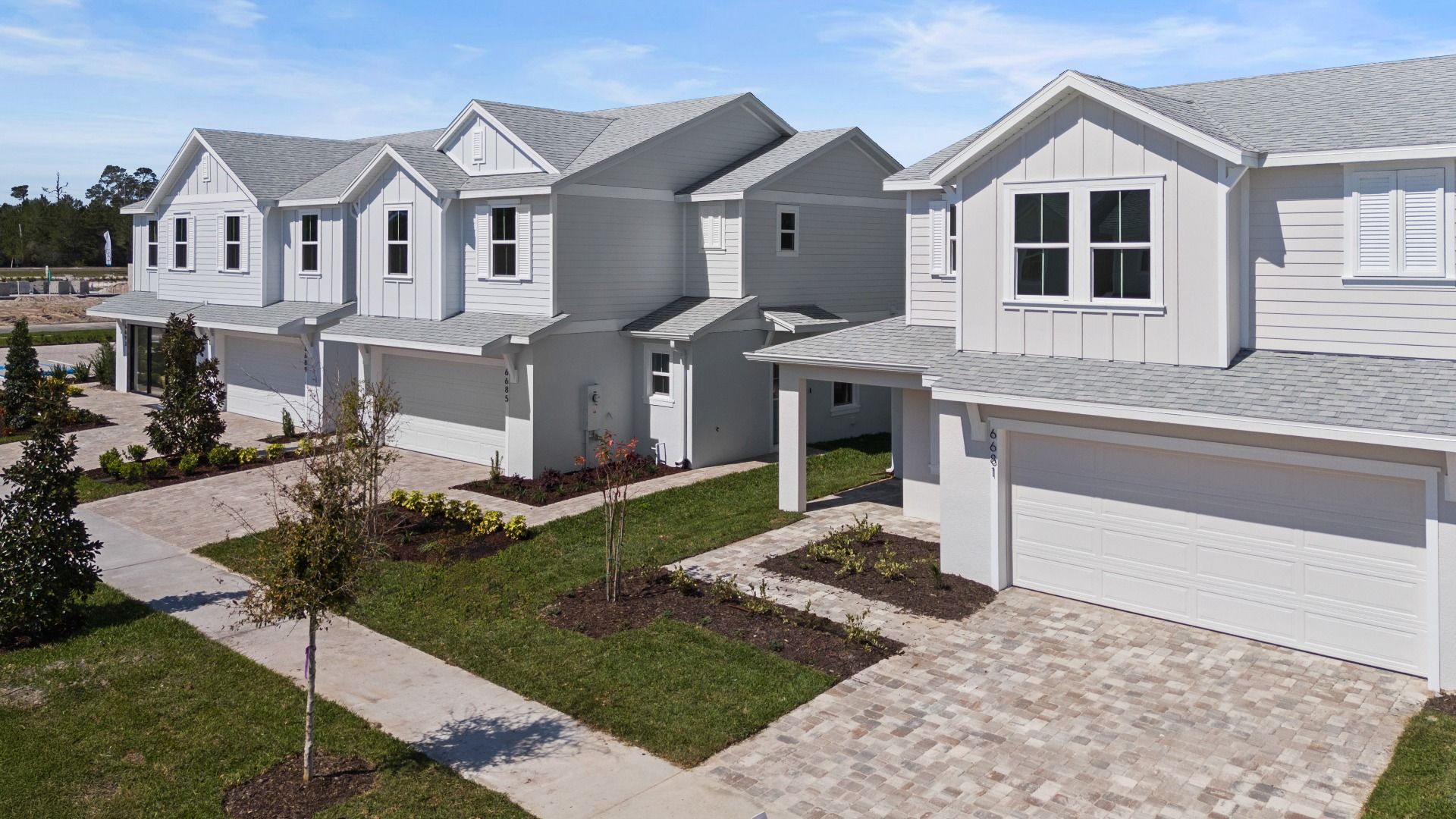 Cyrene at Harmony by DRB Homes features a paver driveway and walkway, enhanced by beautiful landscaping and serene lake views