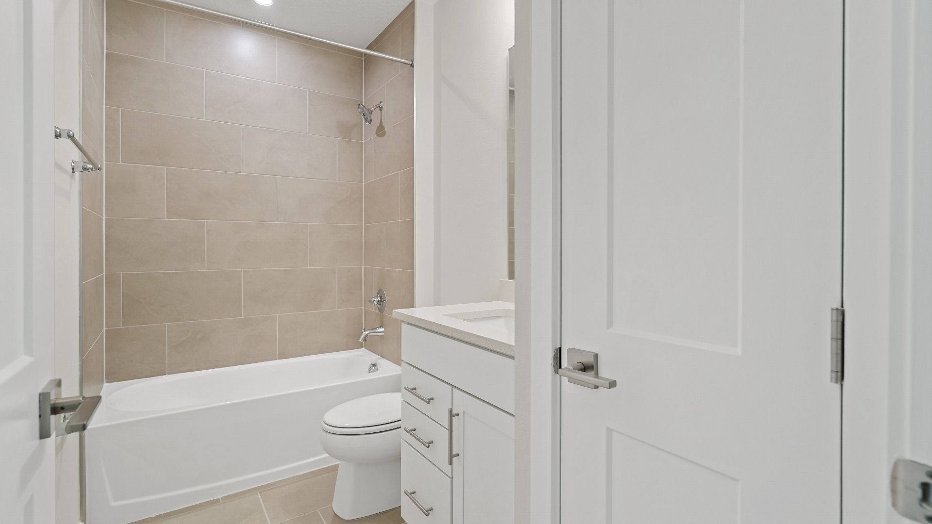 Guest bathroom in The Atlantic by DRB Homes with tiled shower-tub combo, modern fixtures, and linen closet.