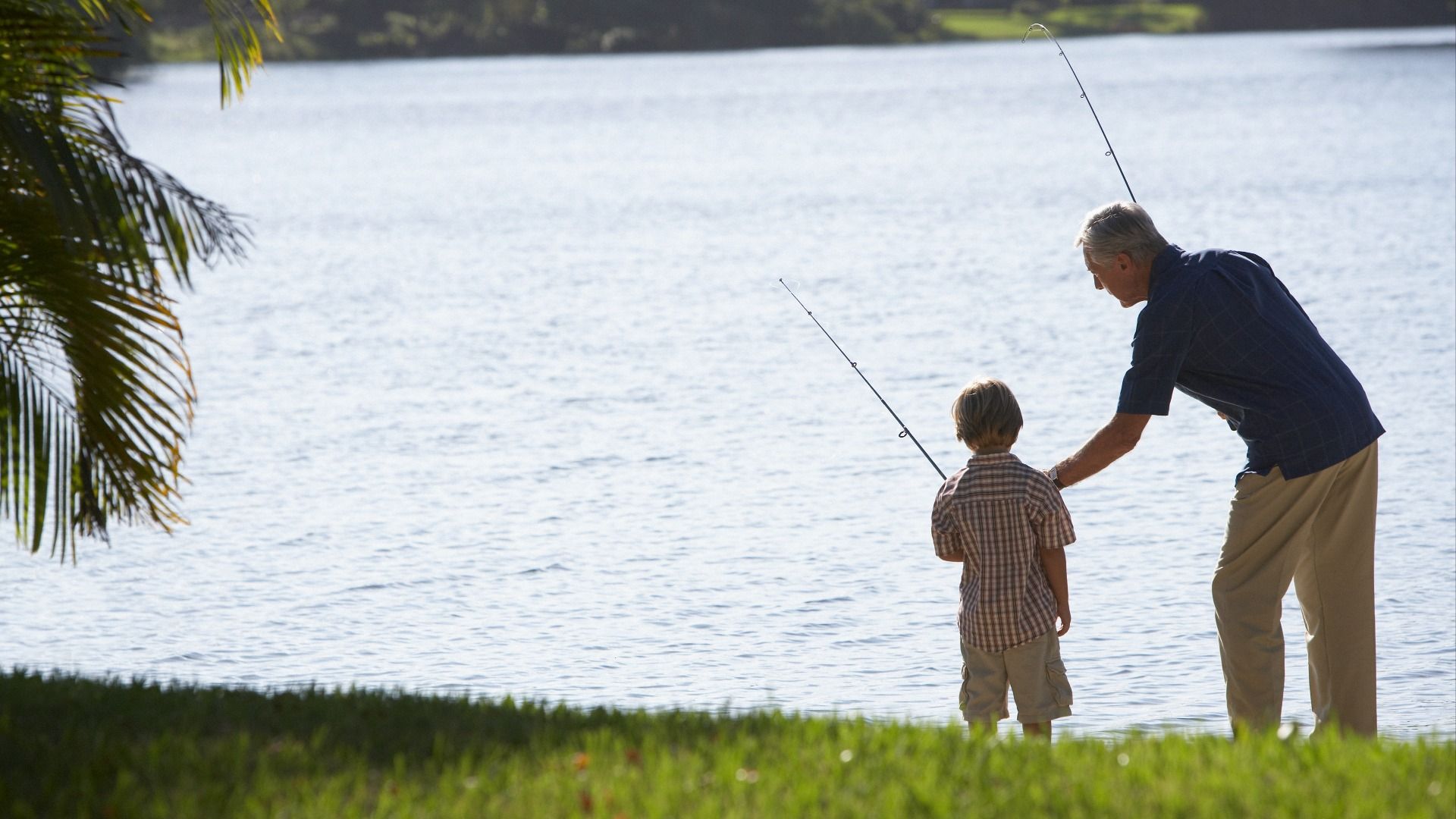 Man and boy enjoying peaceful lake views from the grassy shoreline—capturing quality time in a serene outdoor setting.